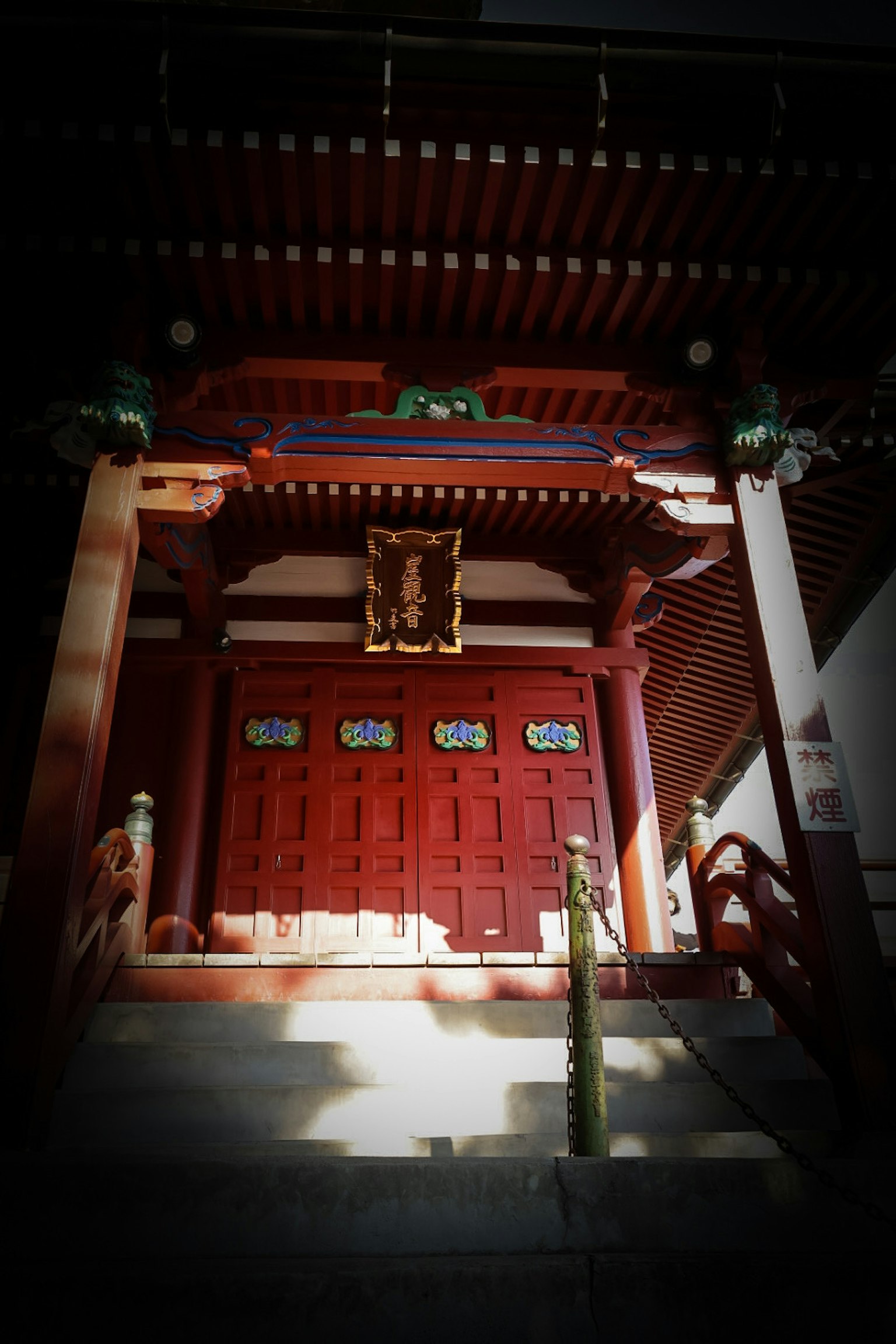 Entrée d'un temple japonais traditionnel avec une porte rouge et un toit orné