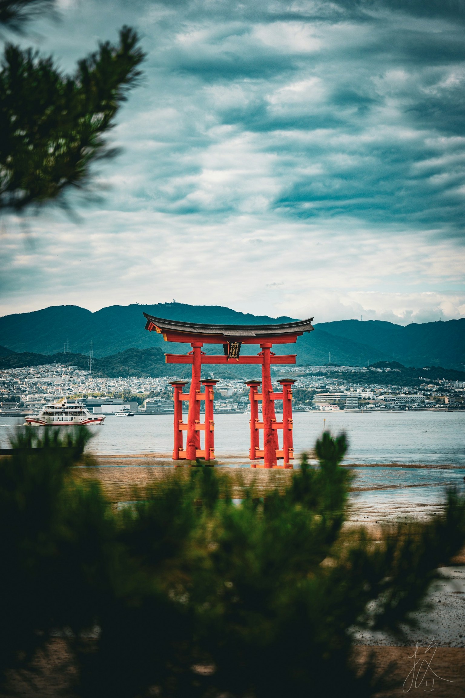 赤い鳥居が海に面した風景で背景には山々が広がる