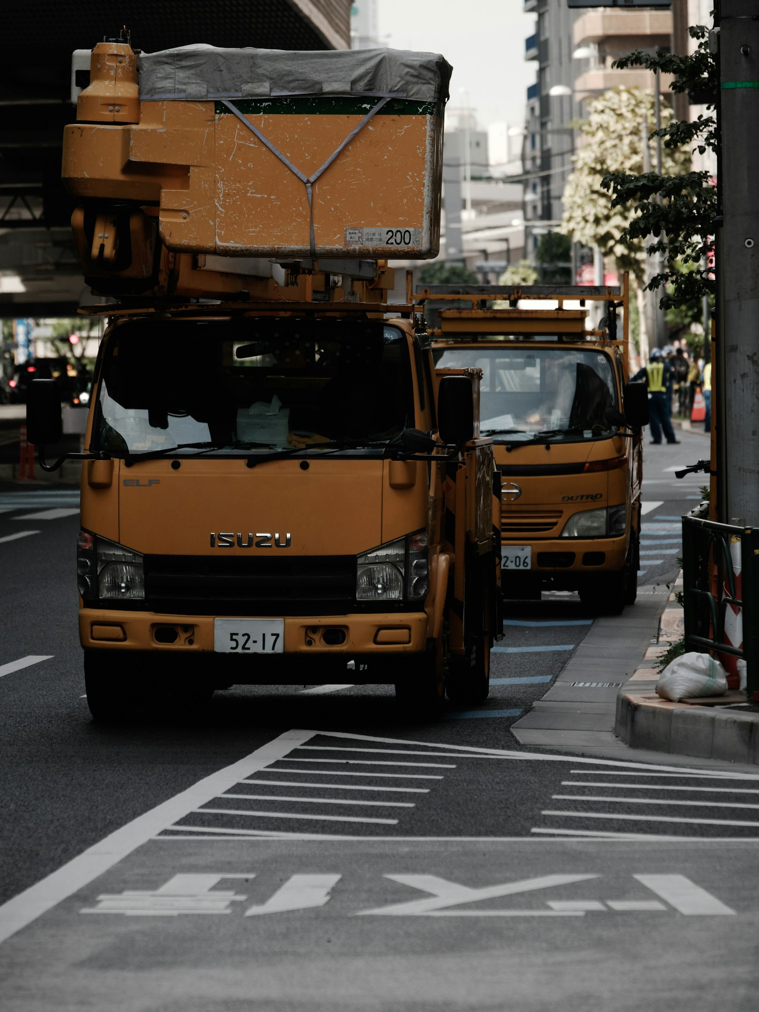 Yellow work truck parked on the street with another vehicle behind it