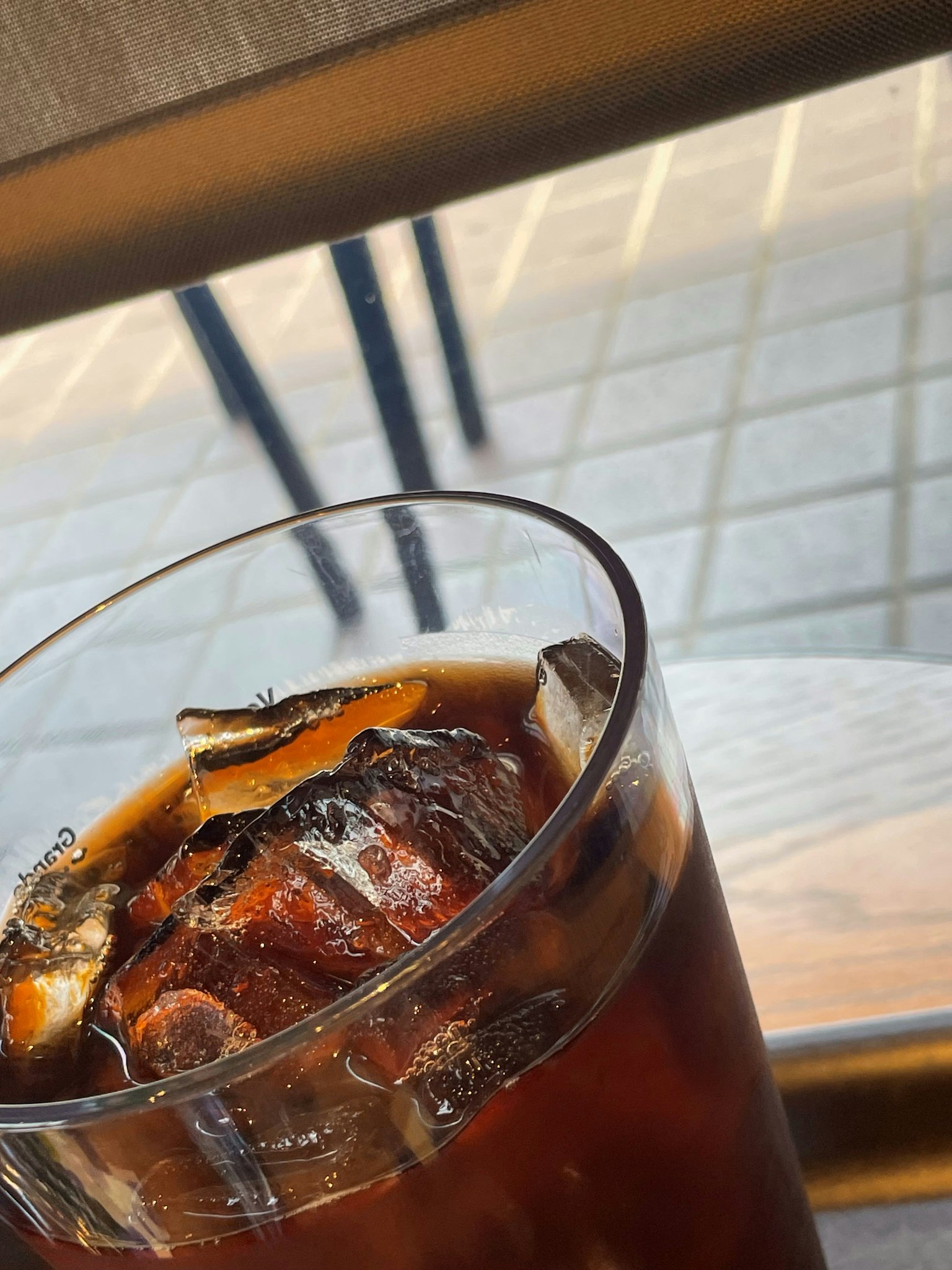 Bicchiere di caffè freddo con cubetti di ghiaccio su un tavolo di legno