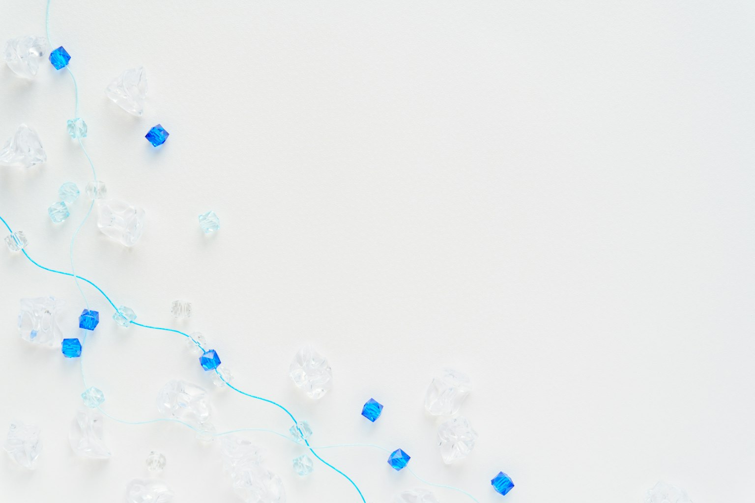 Blue and clear beads scattered on a white background