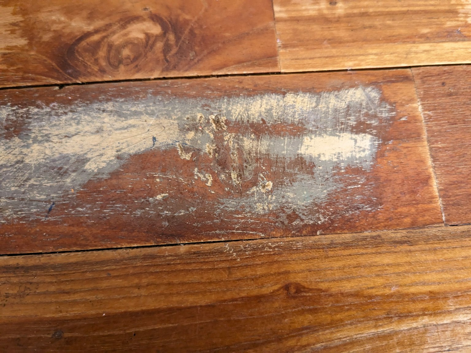 Graffi e zona usurata su pavimento in legno