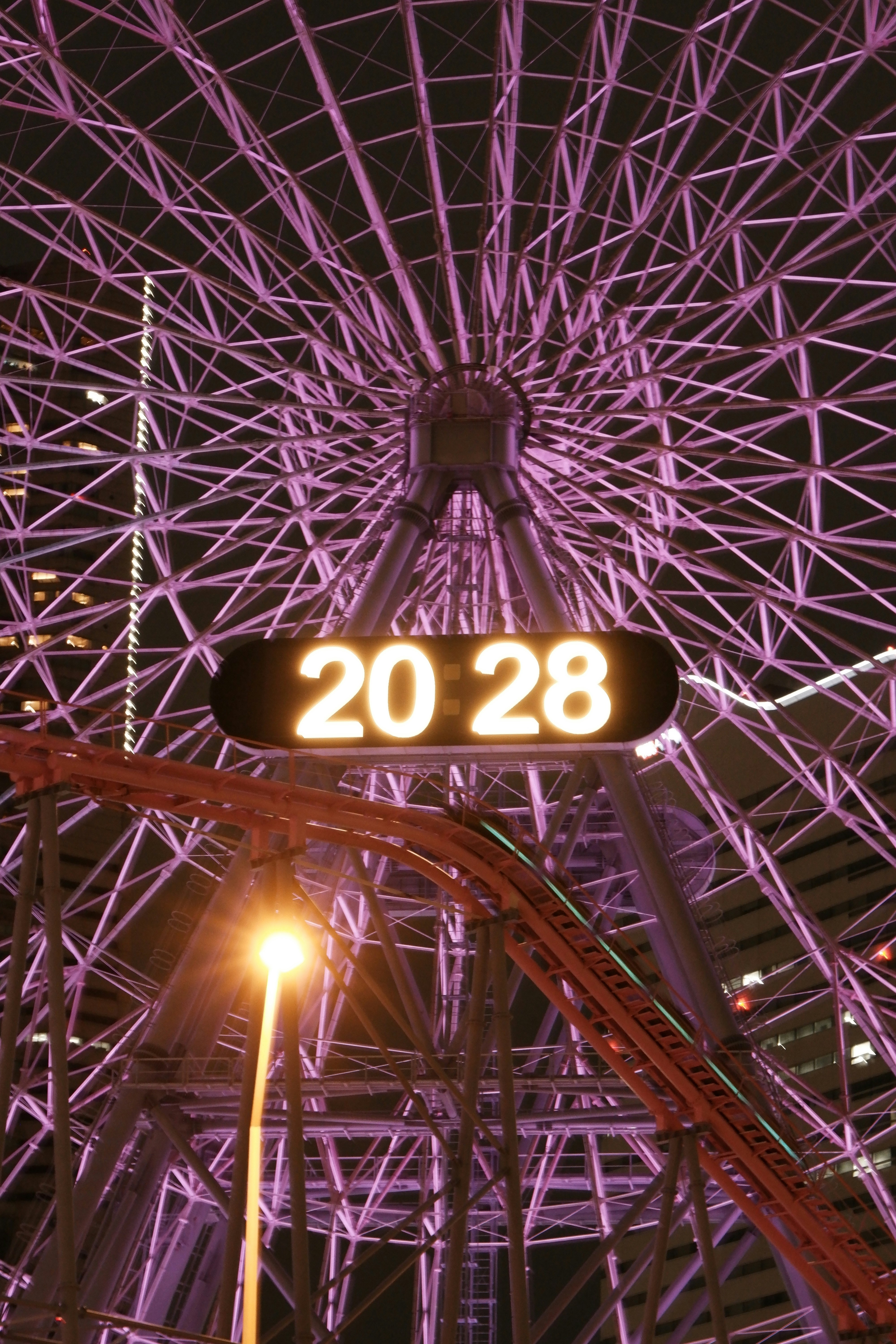 夜のイルミネーションと「20 28」表示のある遊園地の観覧施設