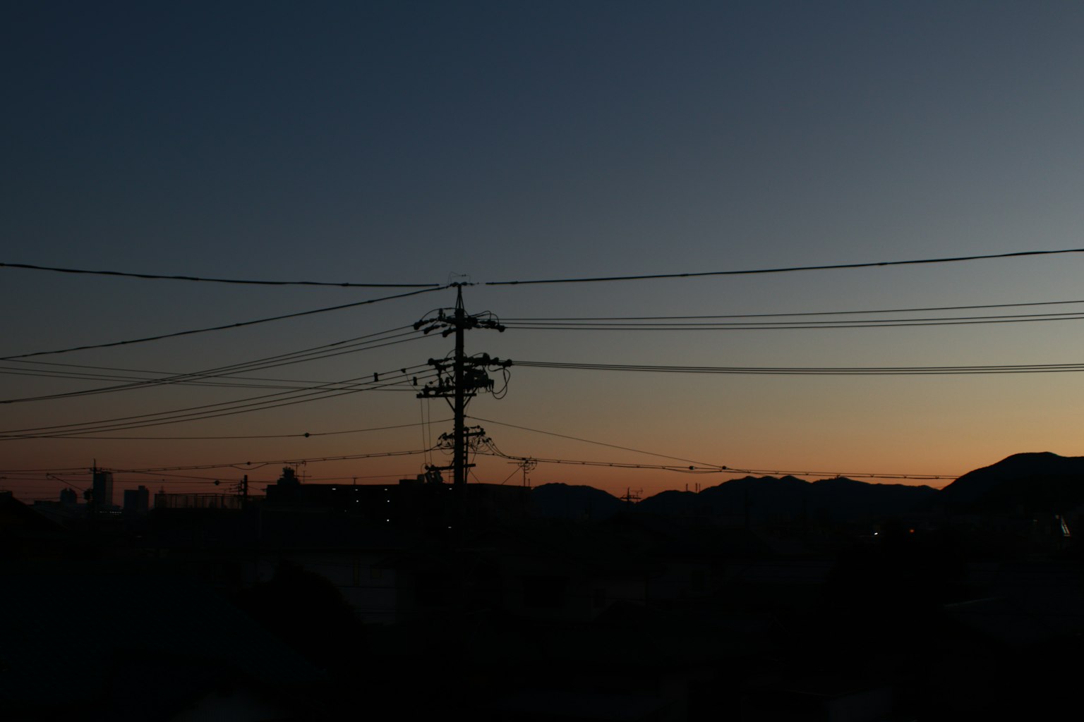 Sonnenuntergangshimmel mit silhouettierten Bergen und Stromleitungen