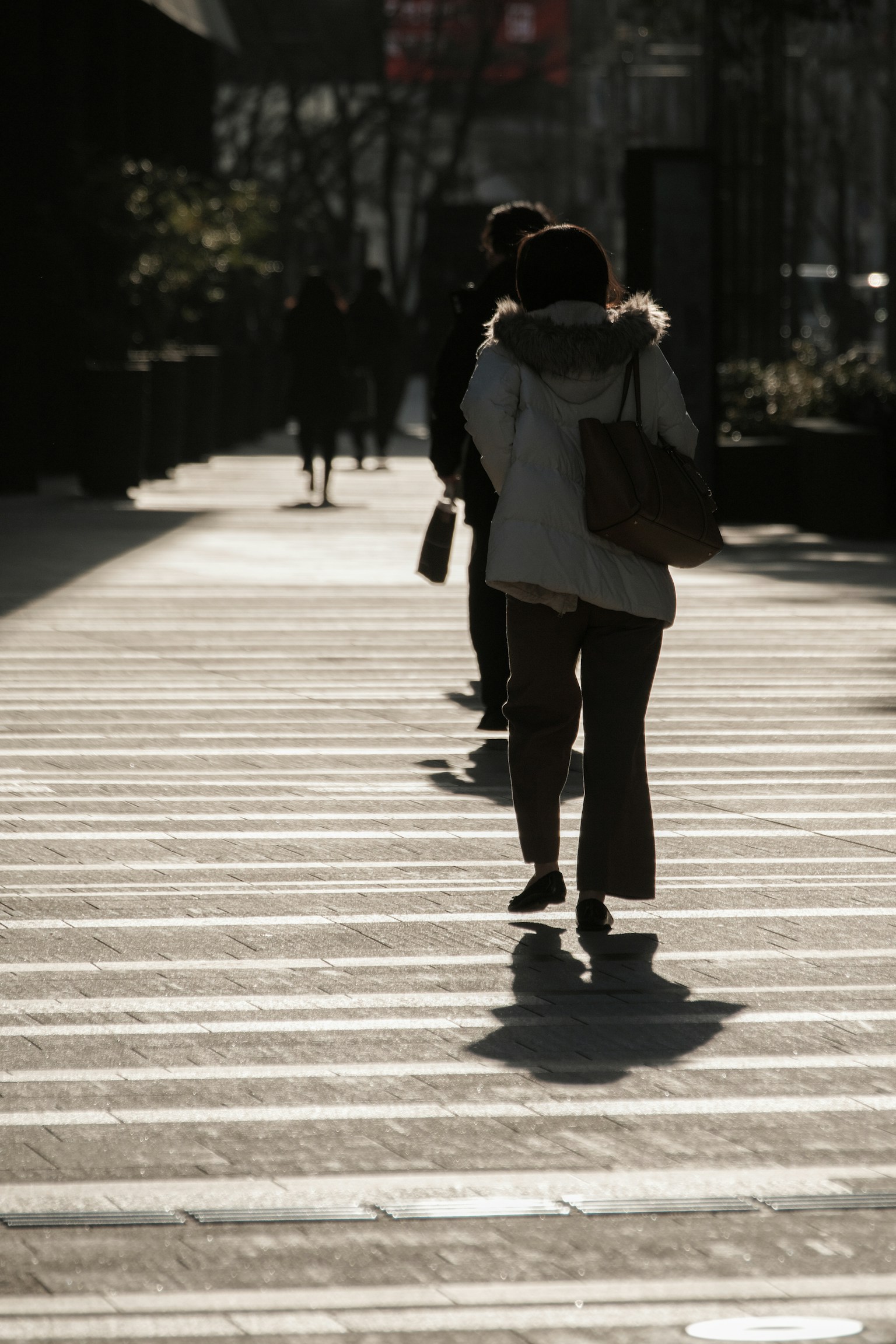 Figure in controluce che camminano su un attraversamento pedonale a strisce