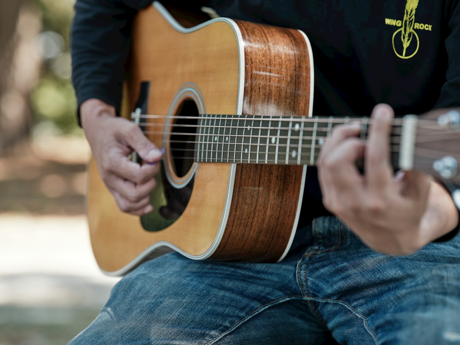 Close-up orang yang memainkan gitar akustik