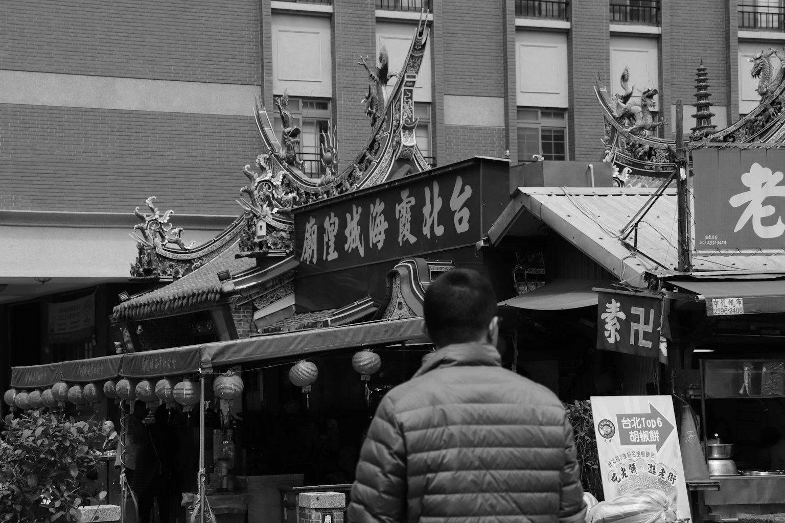Homme regardant un stand de nourriture en noir et blanc dans une rue de marché traditionnel