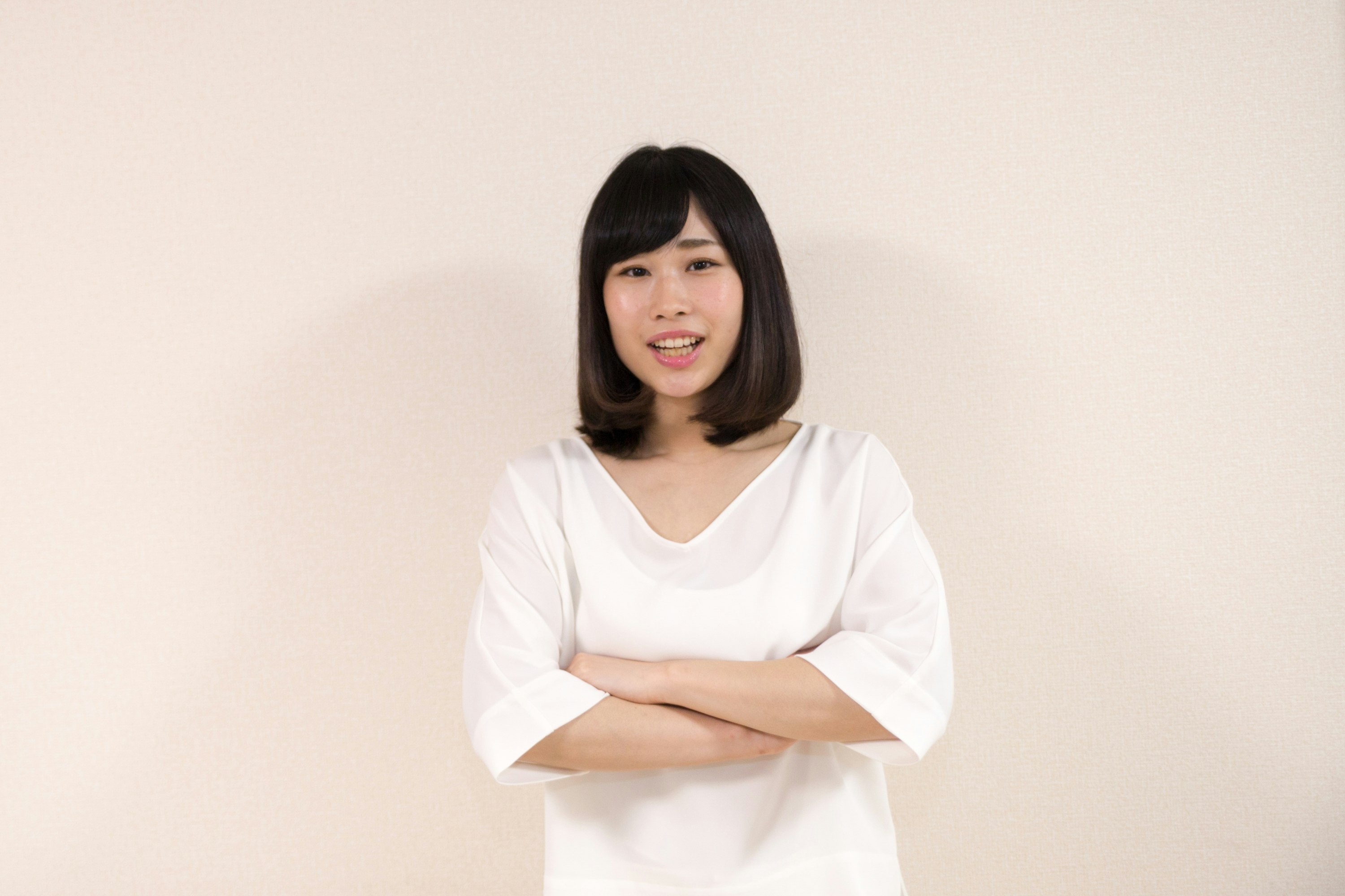白い背景の前で腕を組む女性