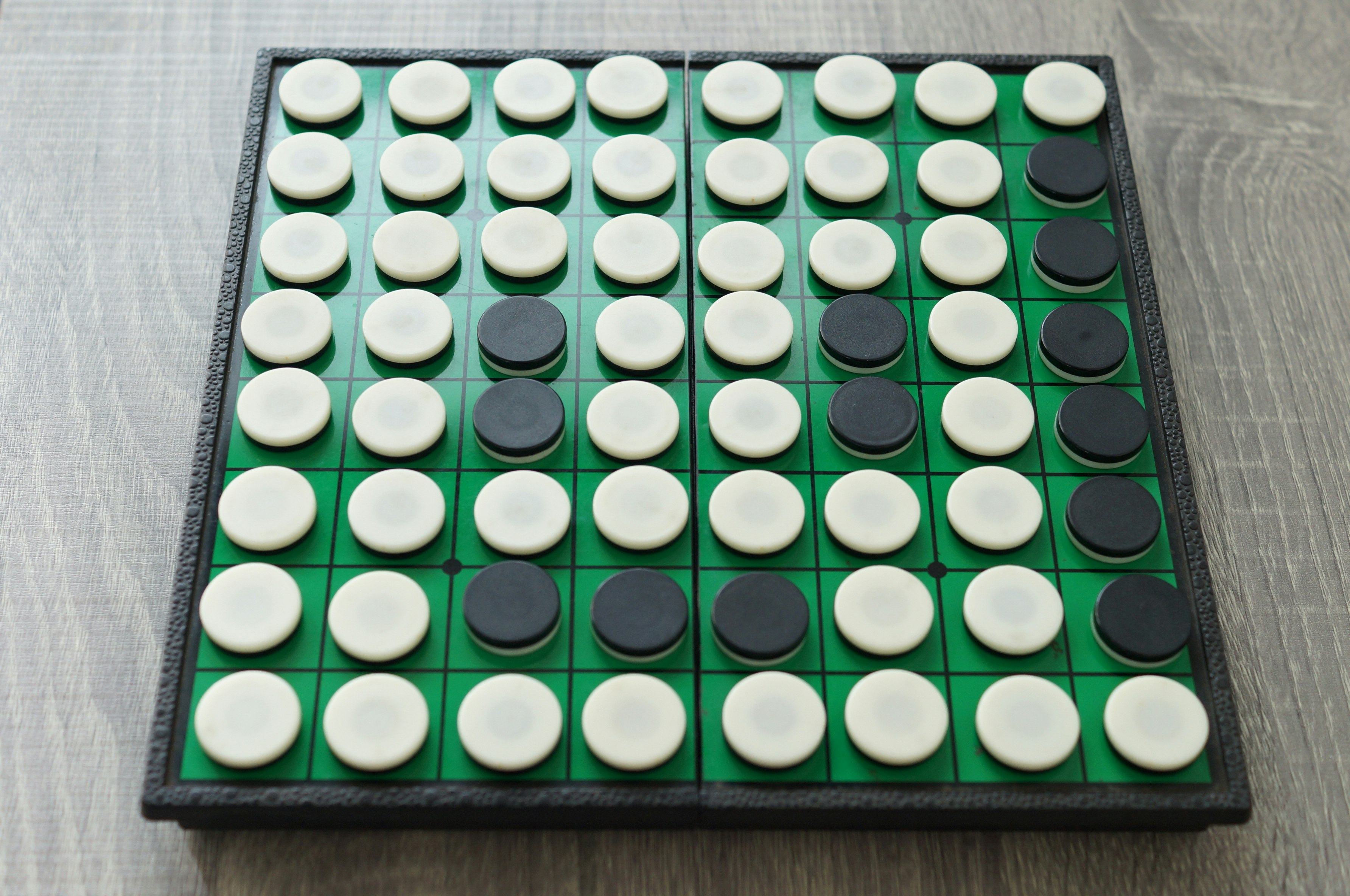 綠色棋盤上排列的白色與黑色棋子影像