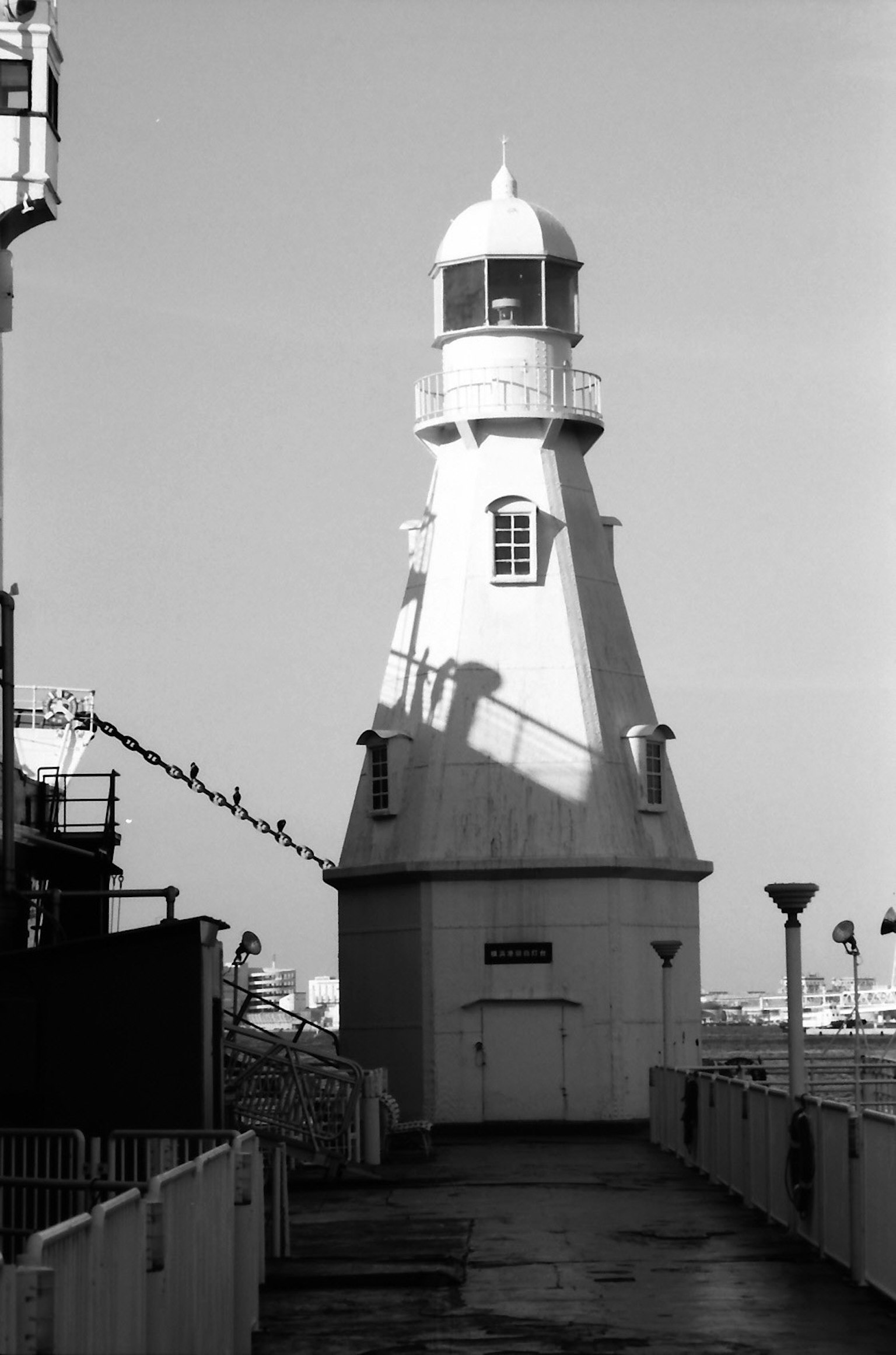 Black and white image of a lighthouse standing by the seaside