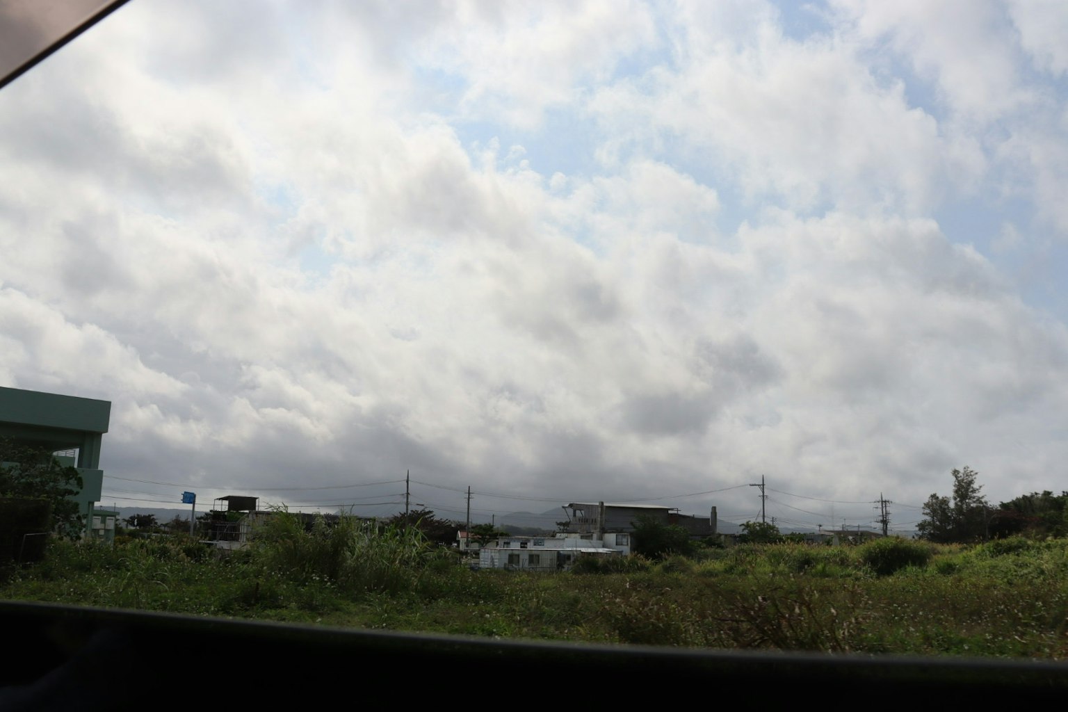 Vista de un cielo nublado sobre campos verdes y edificios