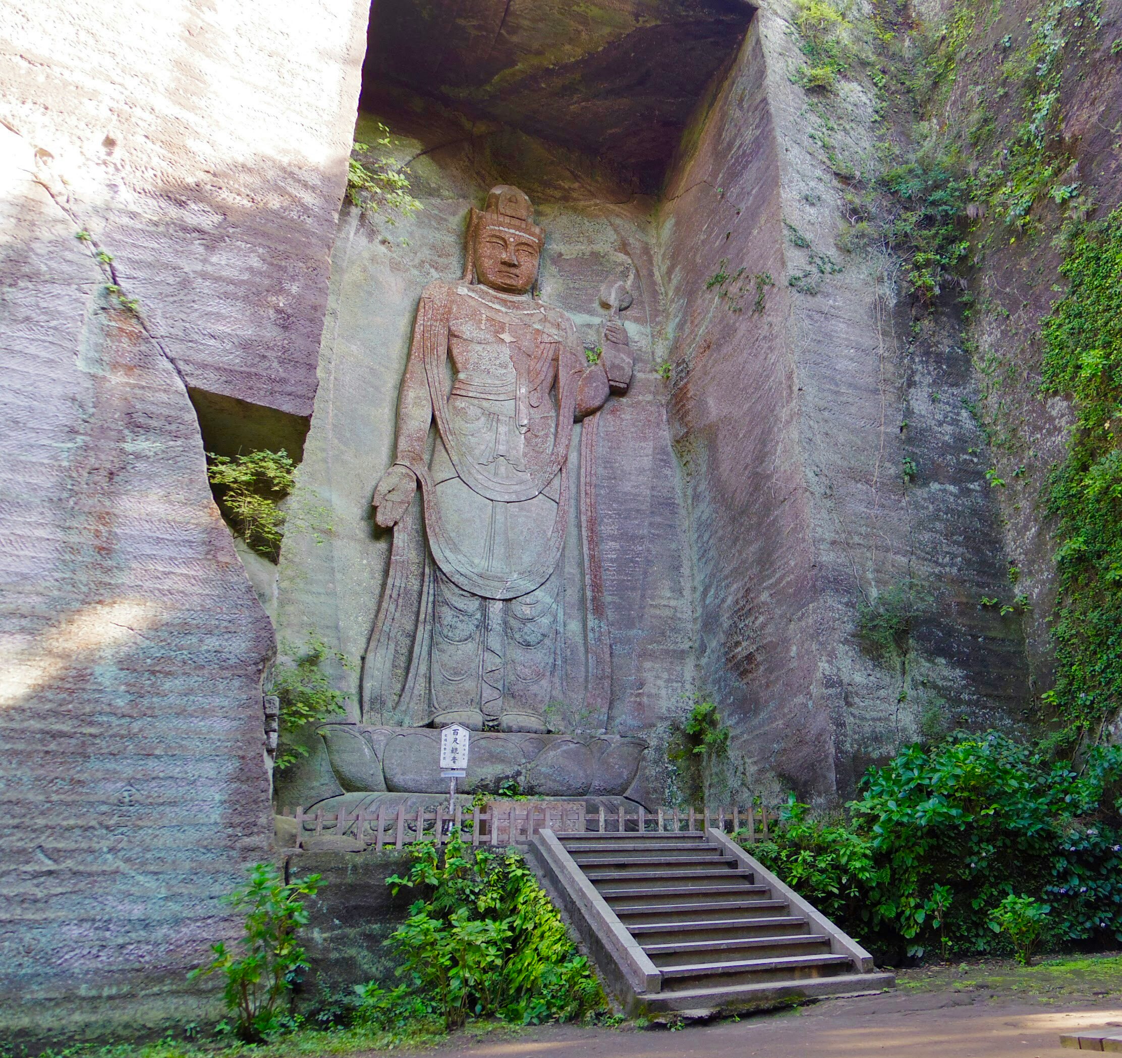 statua del Buddha scolpita nella roccia con gradini in pietra in un contesto di tempio