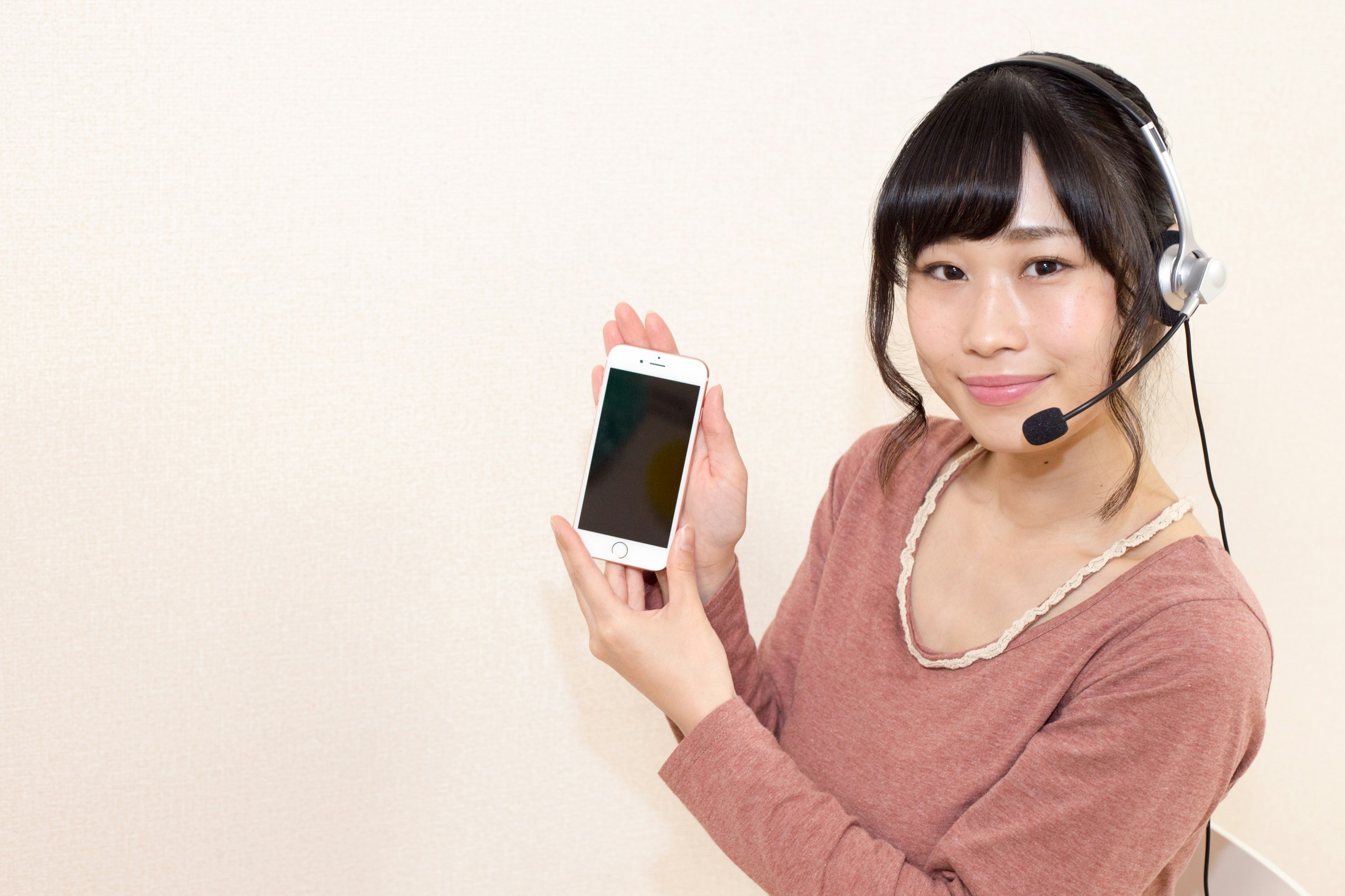 ヘッドセットを付けてスマホを持つ女性