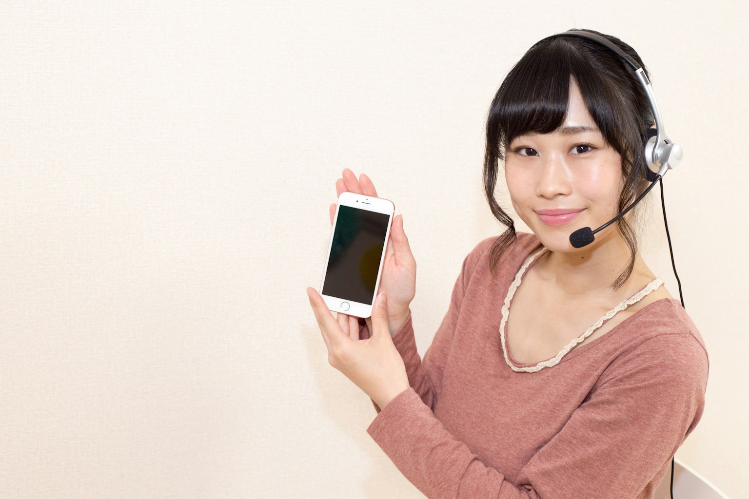 Une femme portant un casque tenant un smartphone et souriant