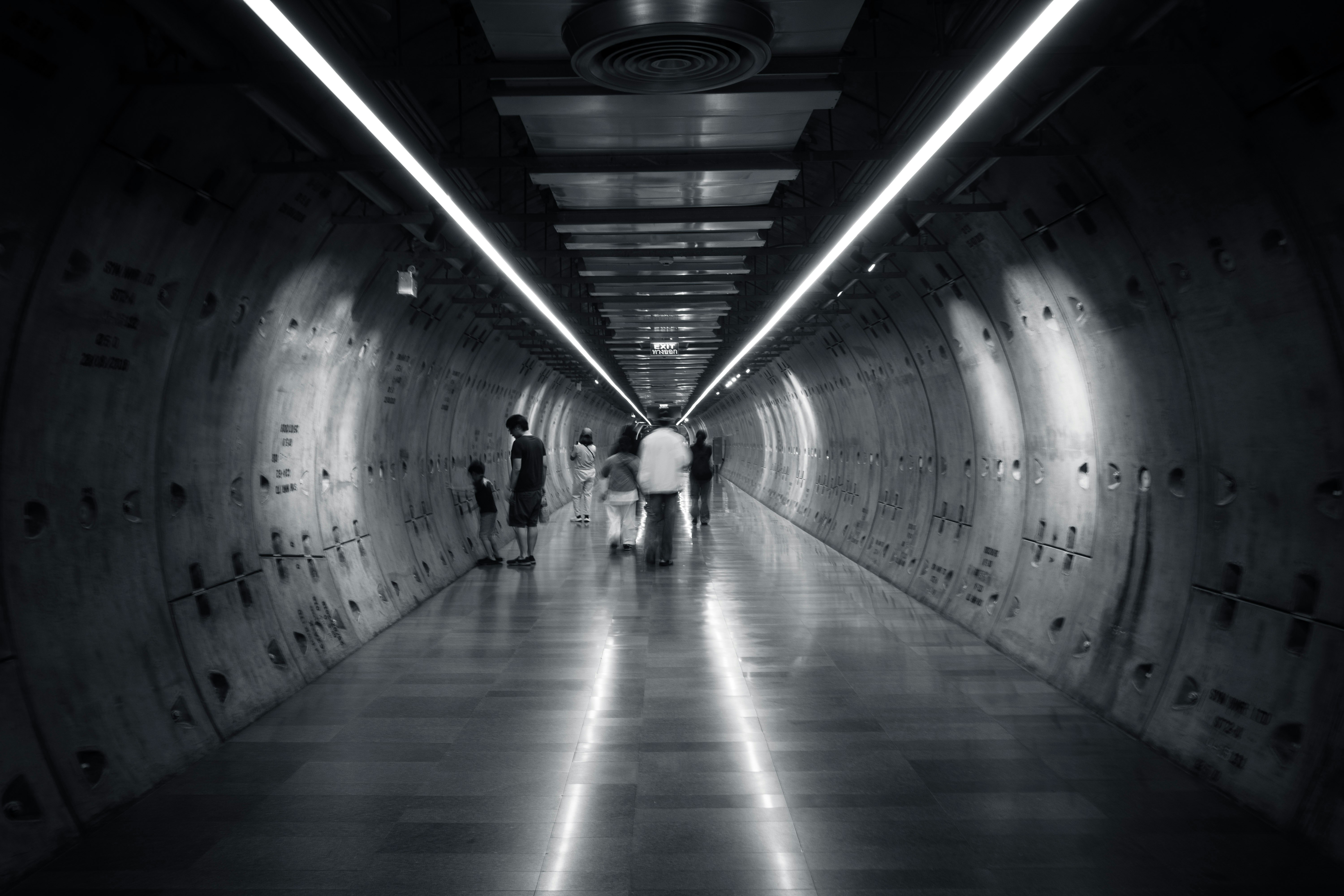 silhouettes de personnes marchant dans un long couloir de tunnel