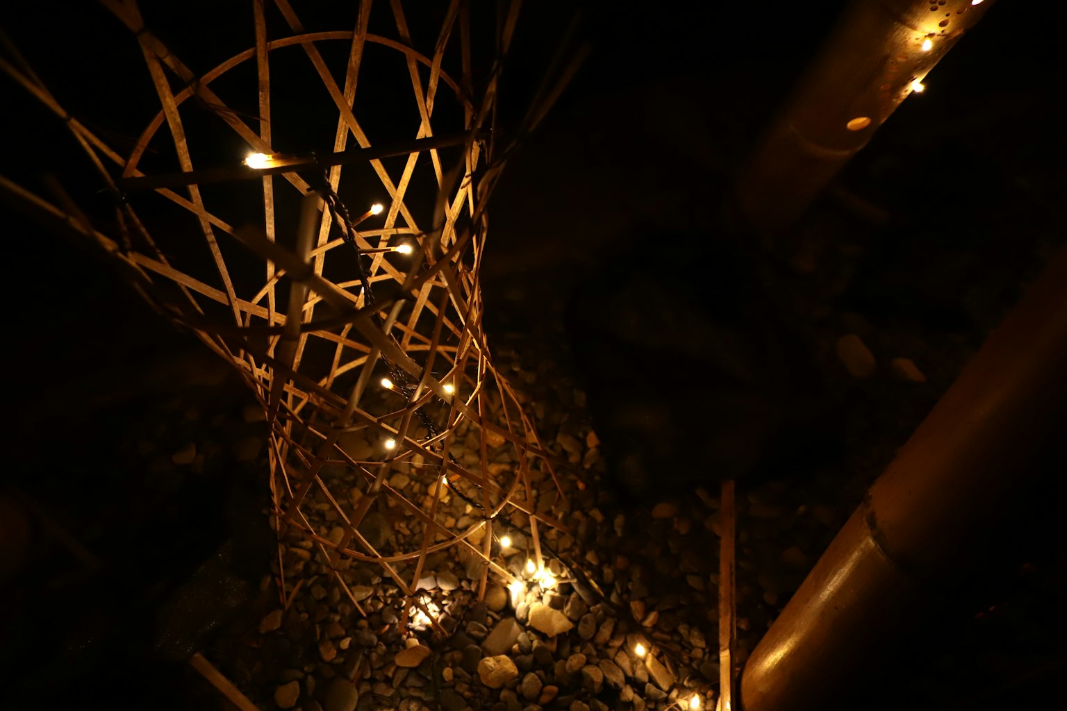 Une structure en bambou illuminée par de petites lumières sur fond sombre