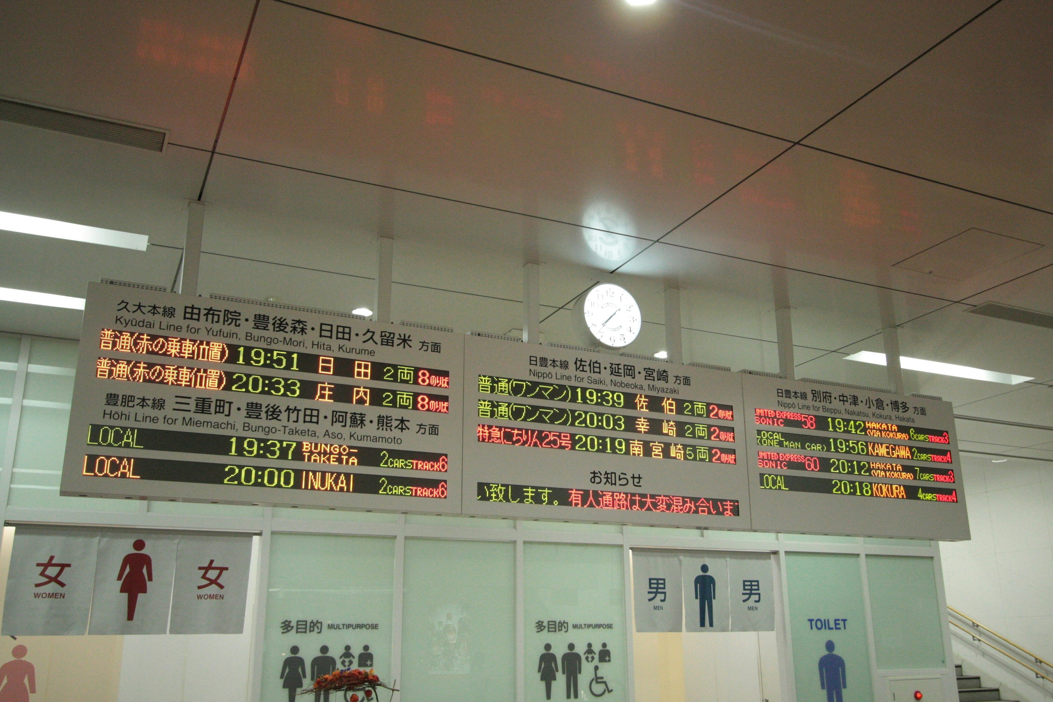 駅の改札付近に掲示された時刻表と案内表示のある壁面