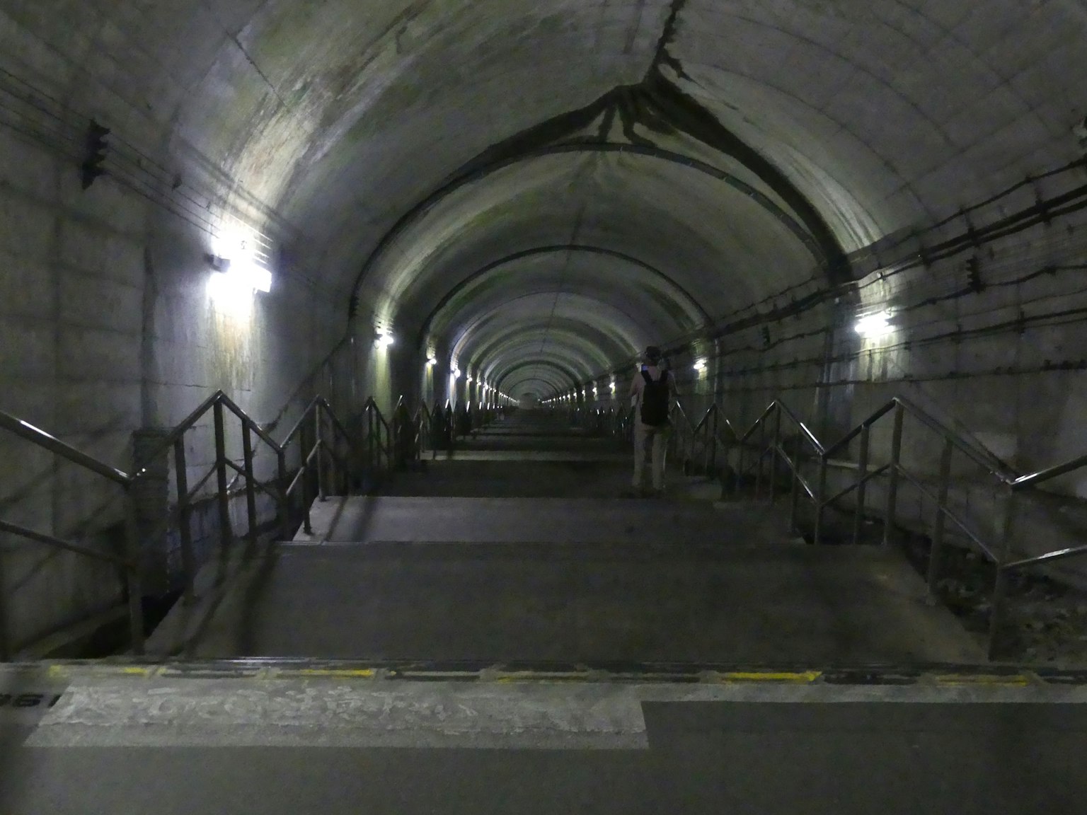 Interior dari terowongan panjang dengan tangga dan pegangan yang terlihat
