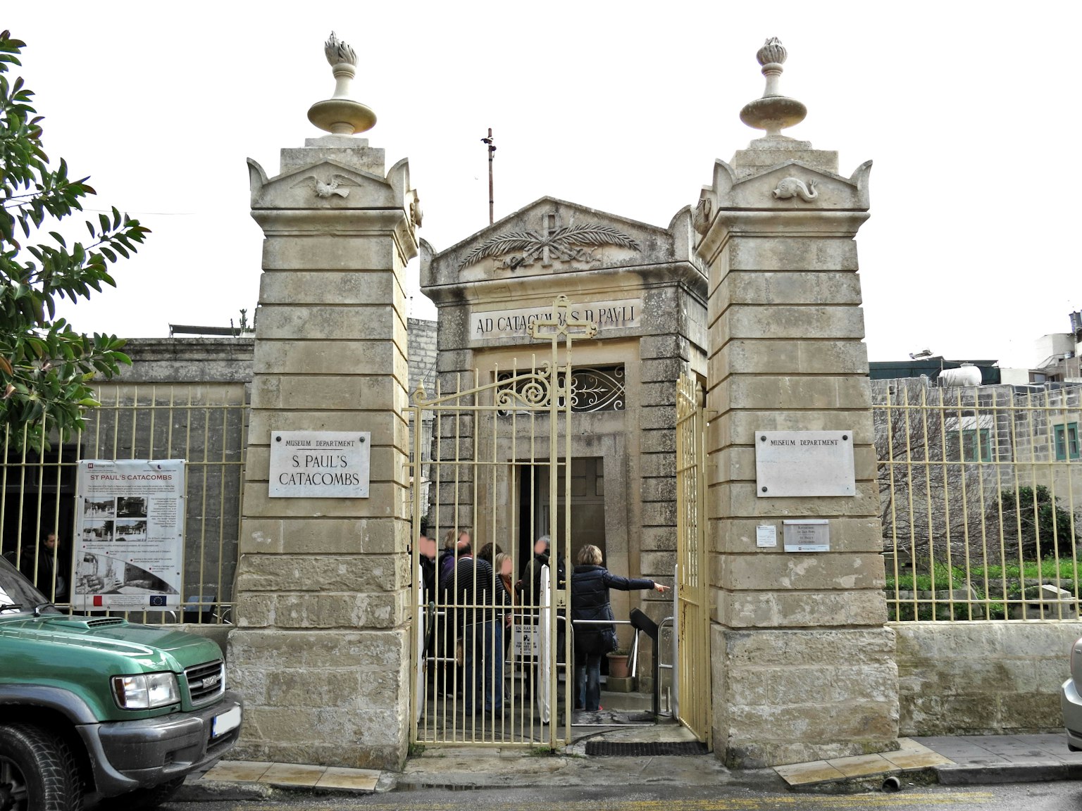 Entrata di un edificio in pietra con cancello metallico e persone che entrano