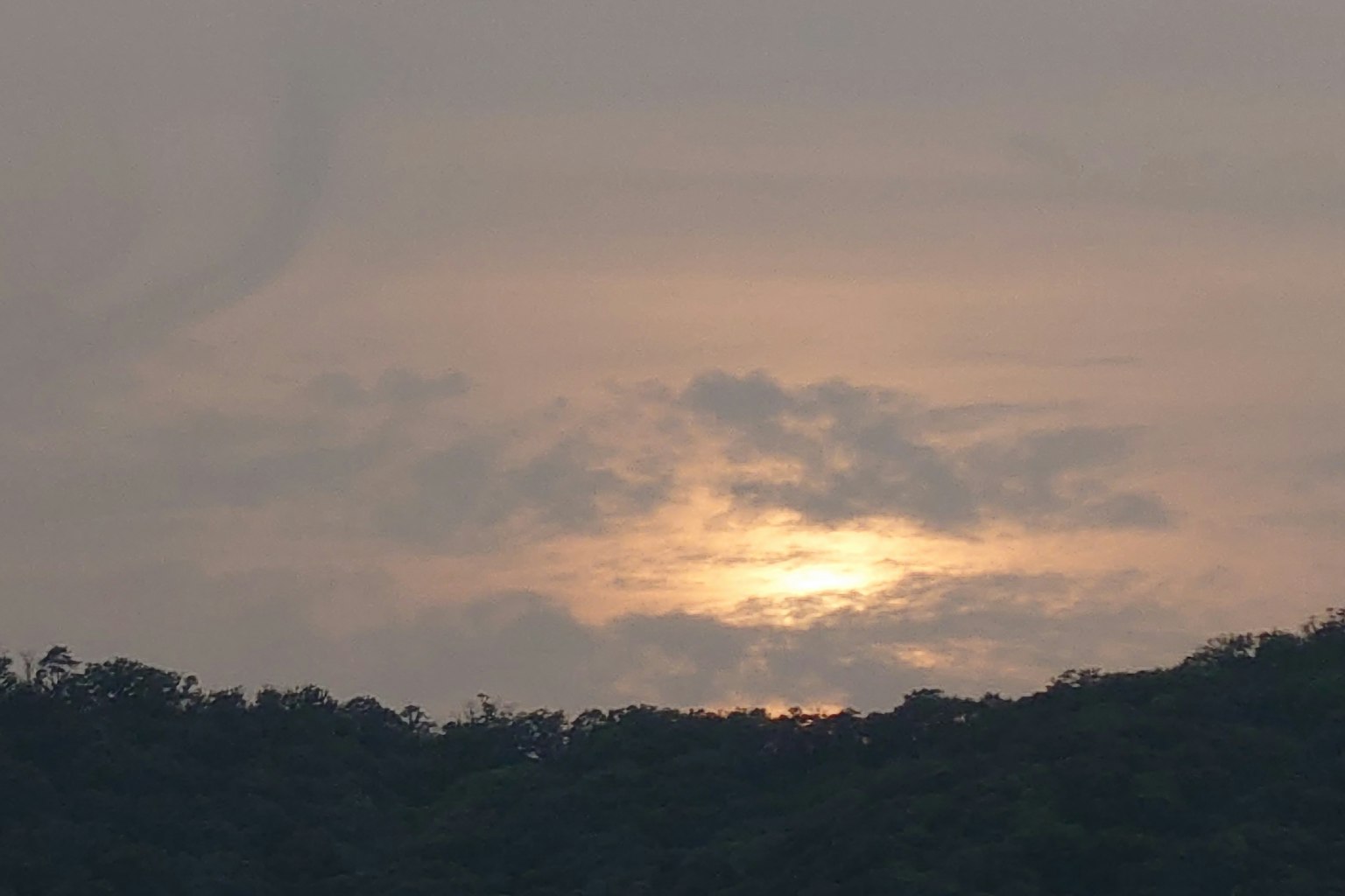 Tramonto dietro le nuvole su una silhouette di montagna