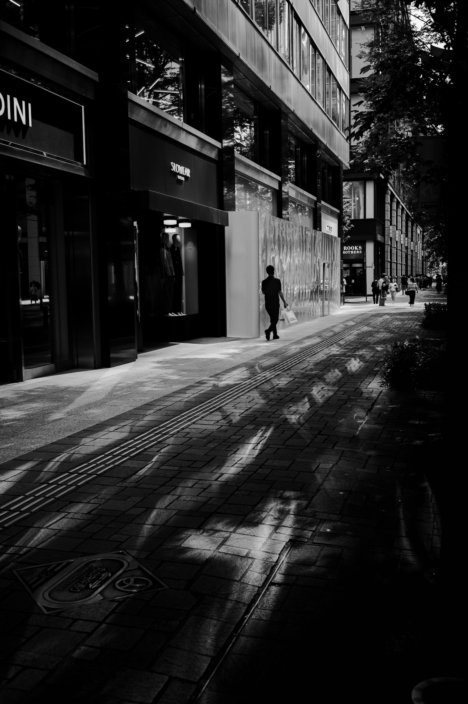 Silhouette einer Person, die in einer schattigen Stadtstraße geht
