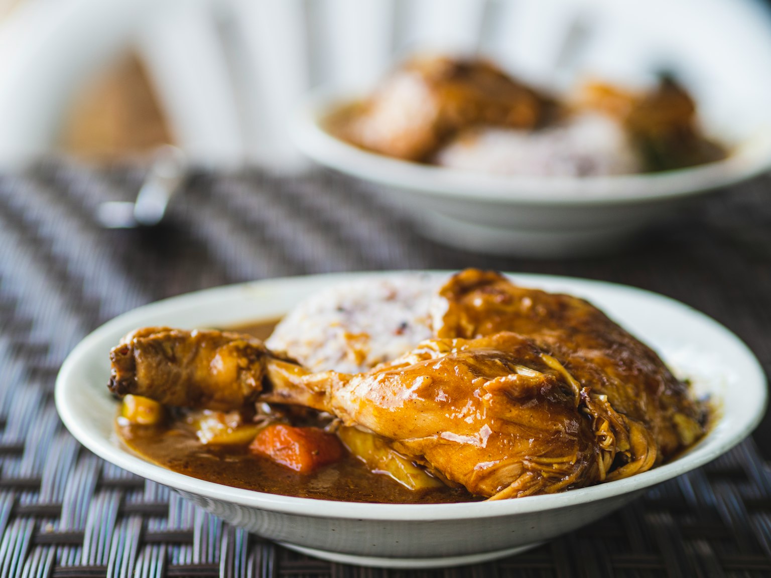 Un plat de ragoût de poulet avec des légumes servi sur une table tressée