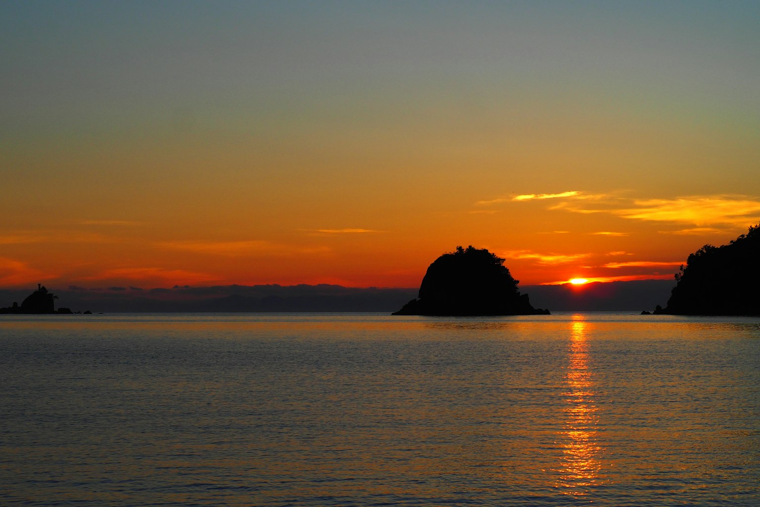 Vue panoramique du coucher de soleil sur la mer calme silhouette des îles réfléchissant sur l'eau