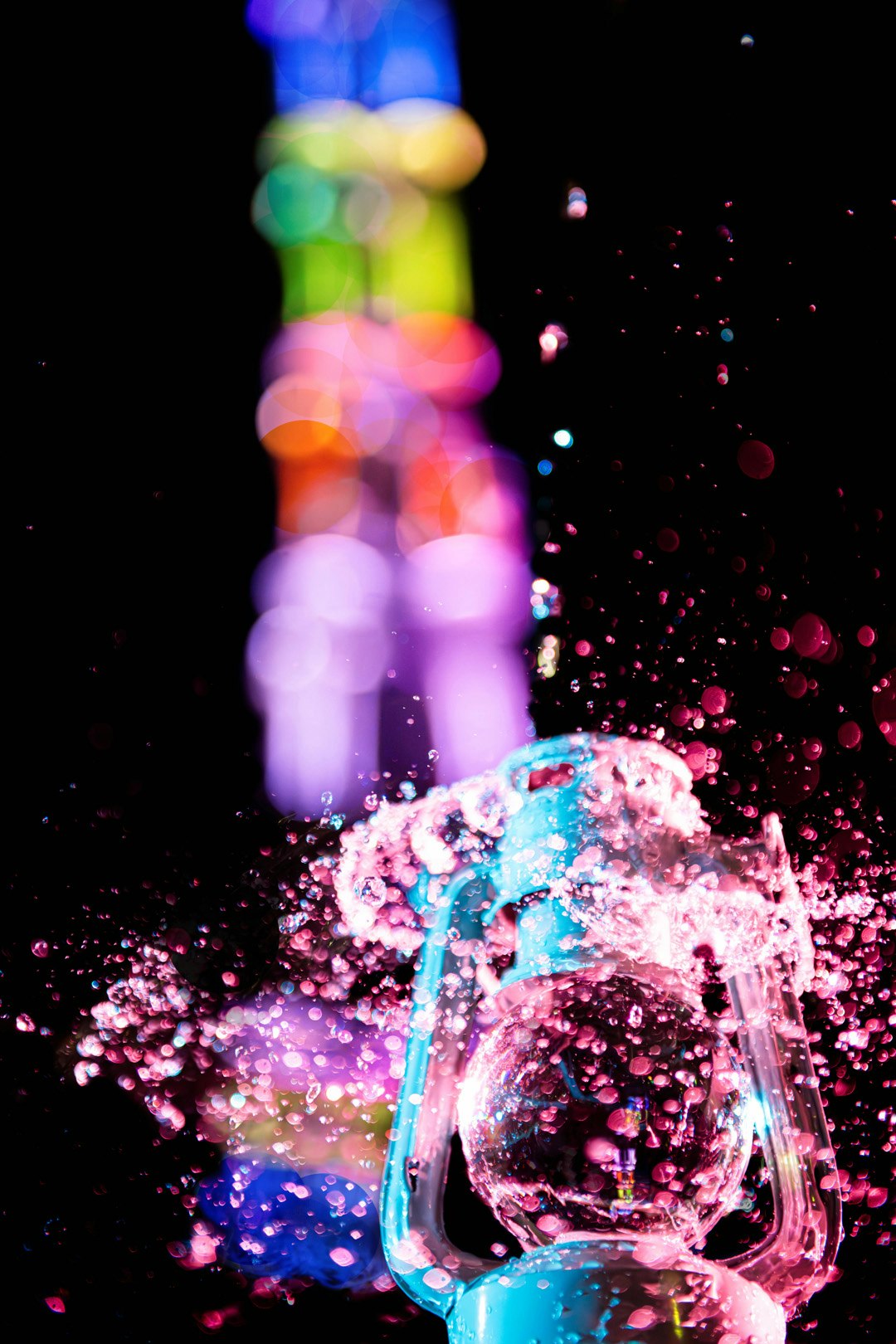 éclaboussures d’eau colorées avec lumière scintillante dans une scène nocturne sombre