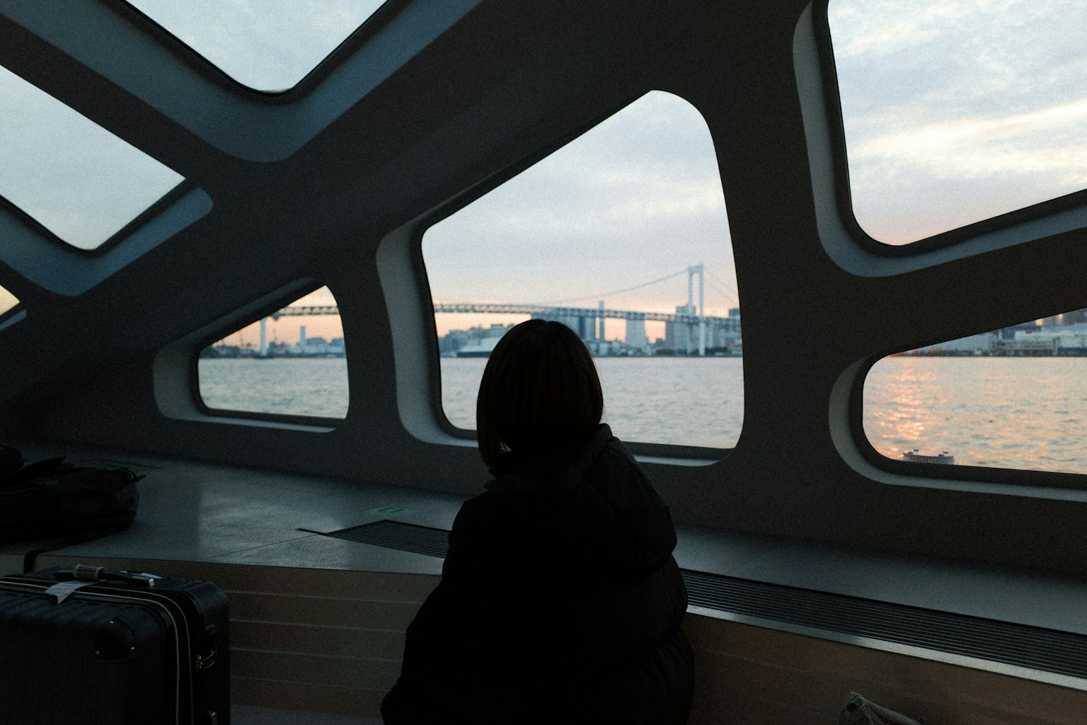 Silhouette of a person against Tokyo Bay and Rainbow Bridge seen through a window