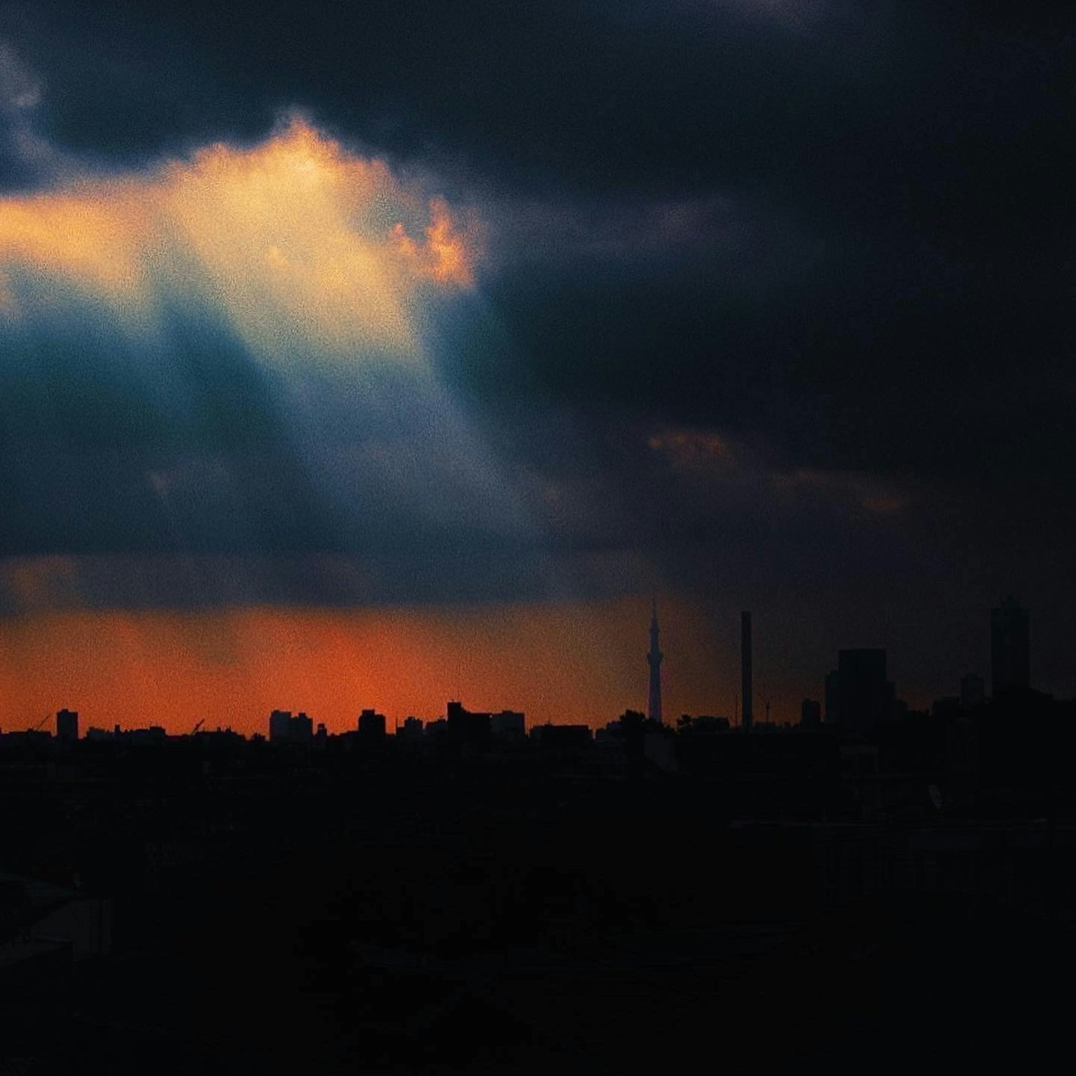 City skyline silhouette with beams of light breaking through dark clouds