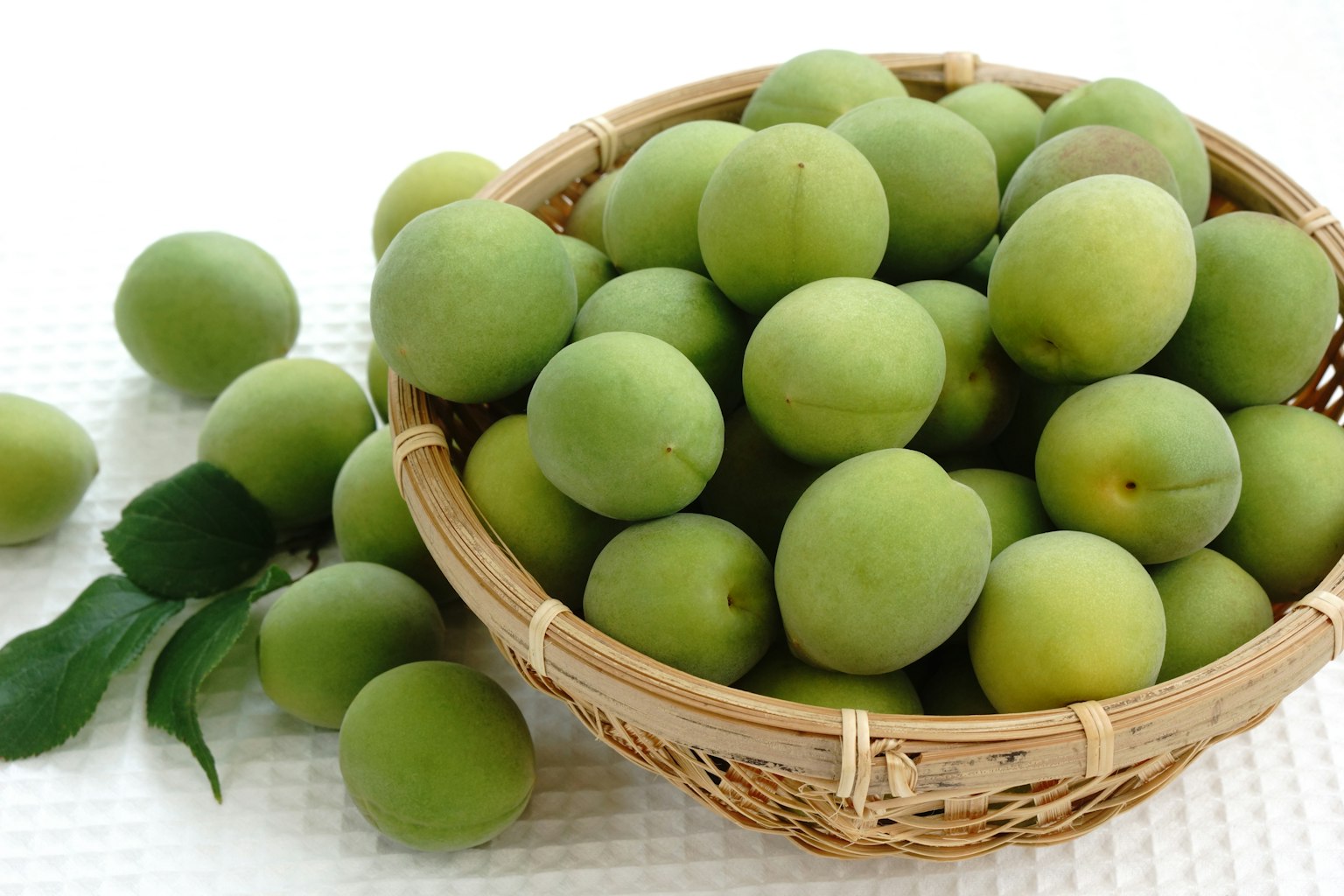 Green plums in a woven basket