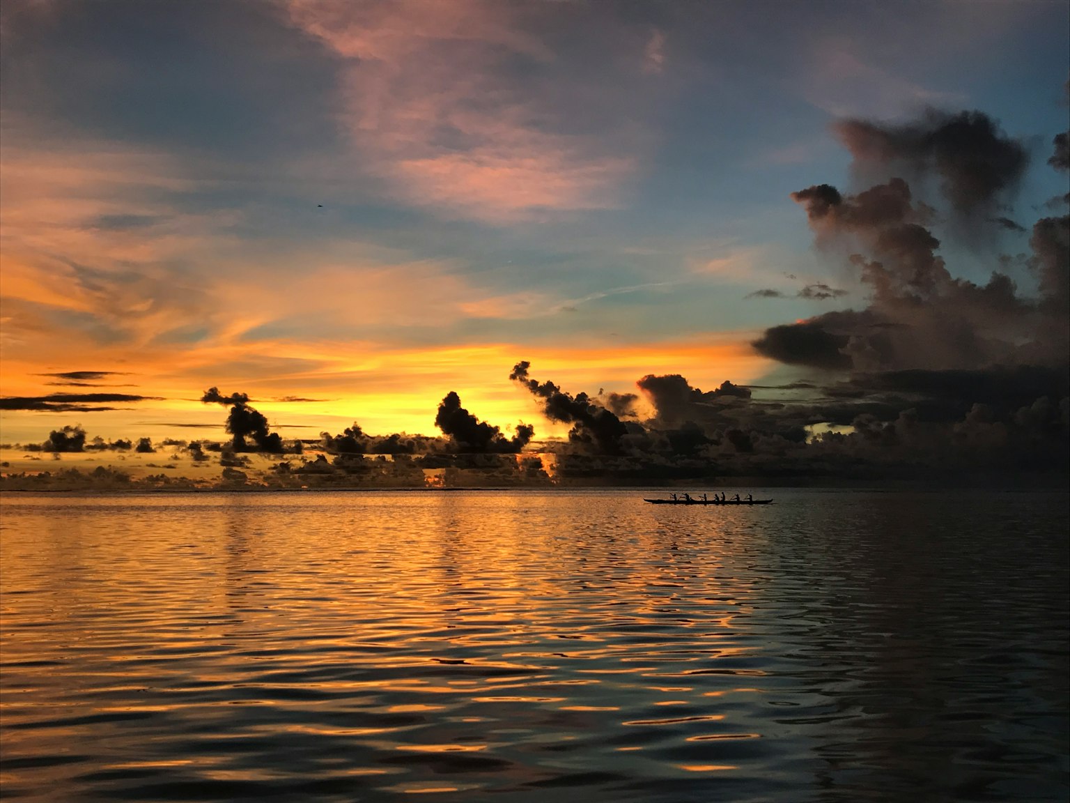 Schöner Sonnenuntergang über dem Ozean mit bunten Reflexionen auf dem Wasser und Wolkensilhouetten