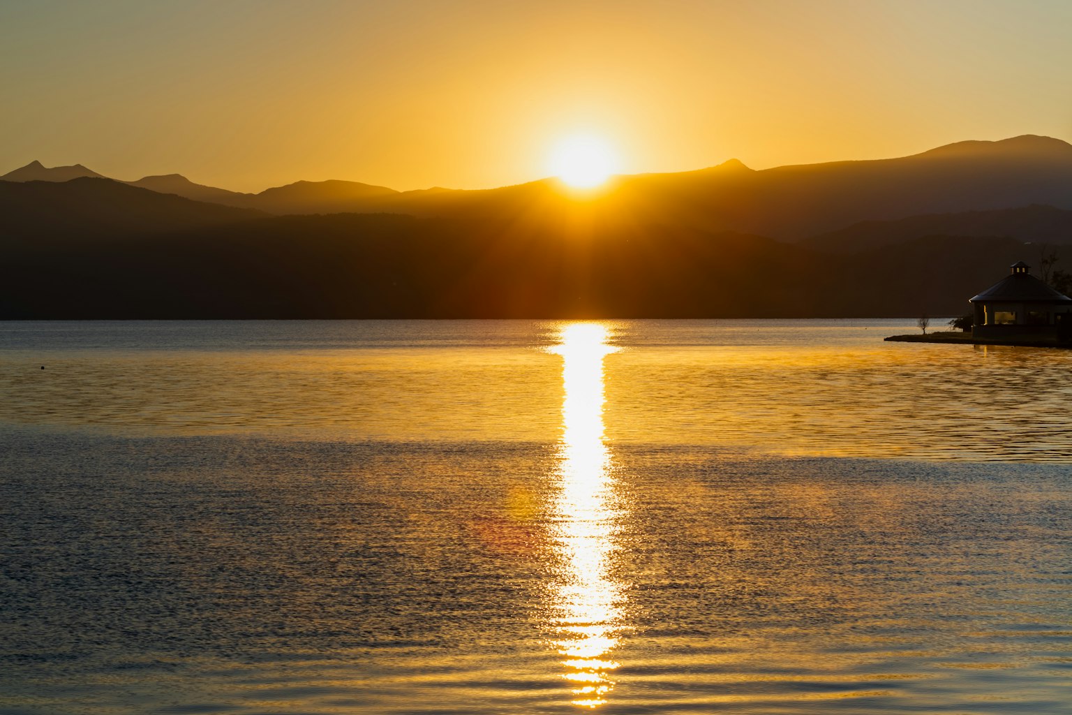 Un hermoso atardecer elevándose entre las montañas reflejado en la superficie del lago