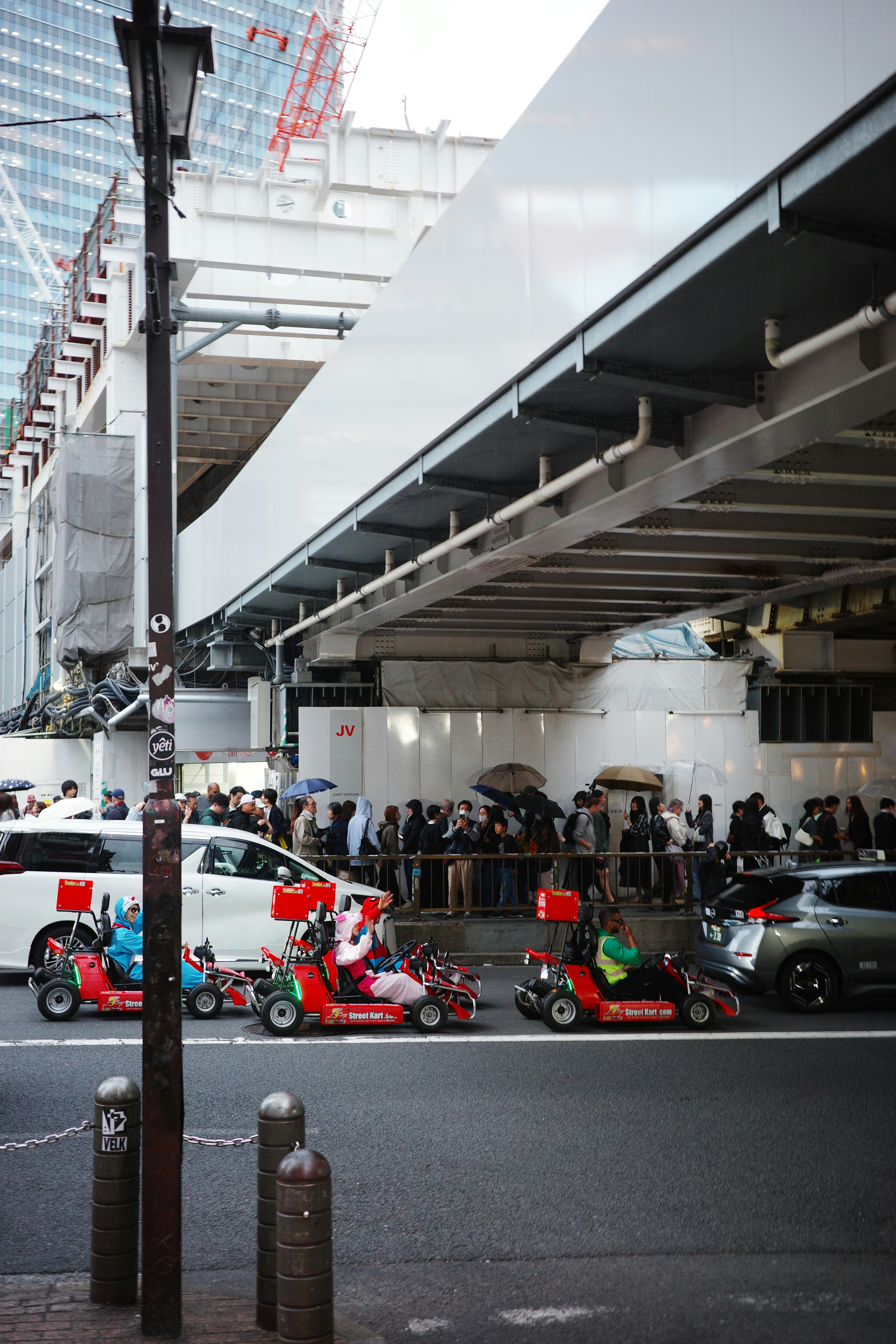 Des personnes en kart sur une rue à Tokyo avec un arrière-plan urbain