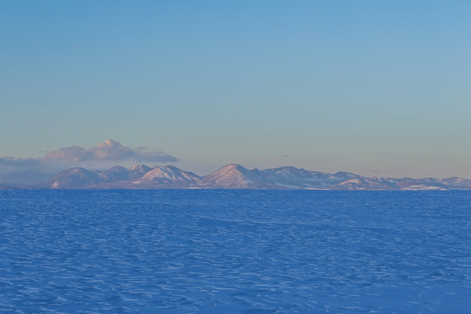 Montañas cubiertas de nieve que se extienden a través de un mar azul