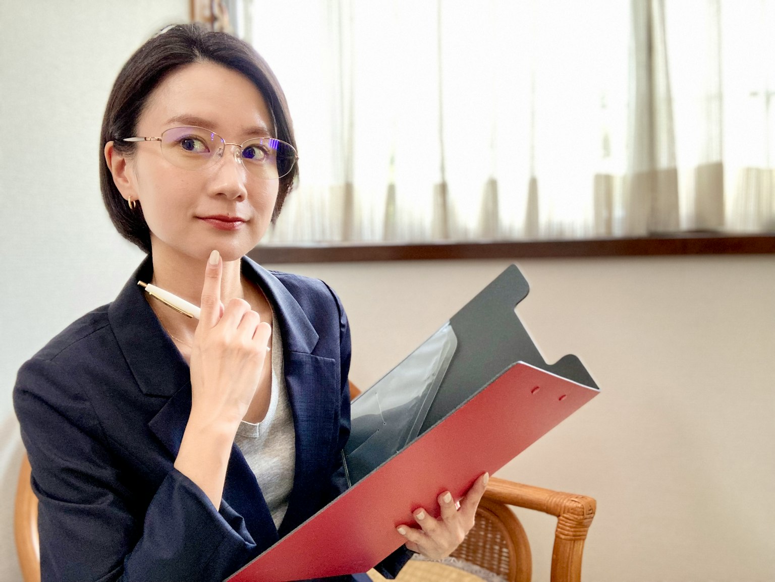 Một người phụ nữ trẻ cầm bảng kẹp và bút trong khi suy nghĩ