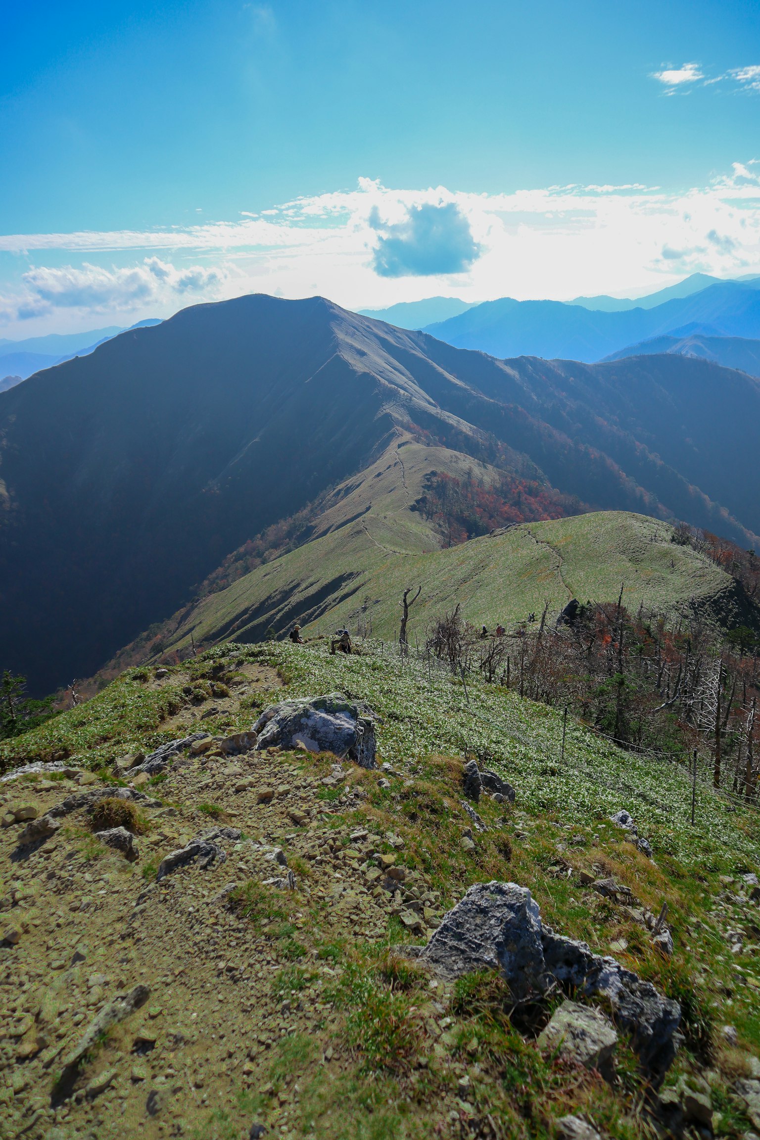 Vista della cresta montuosa con cielo blu erba verde e rocce sparse