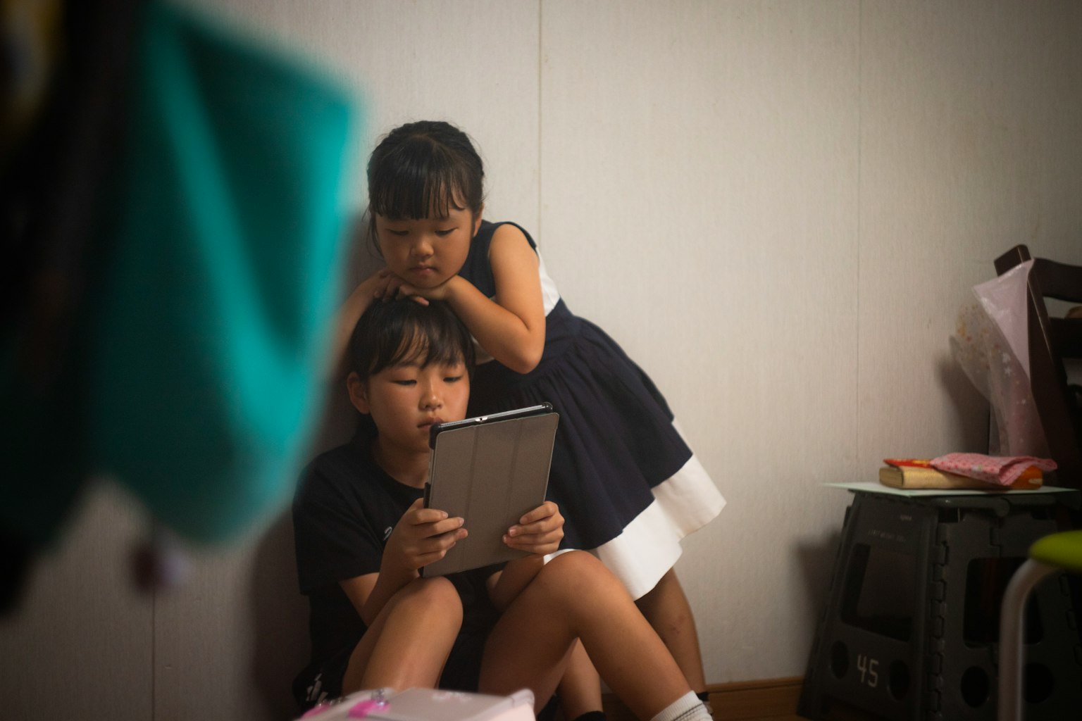 Deux enfants regardant une tablette dans une pièce