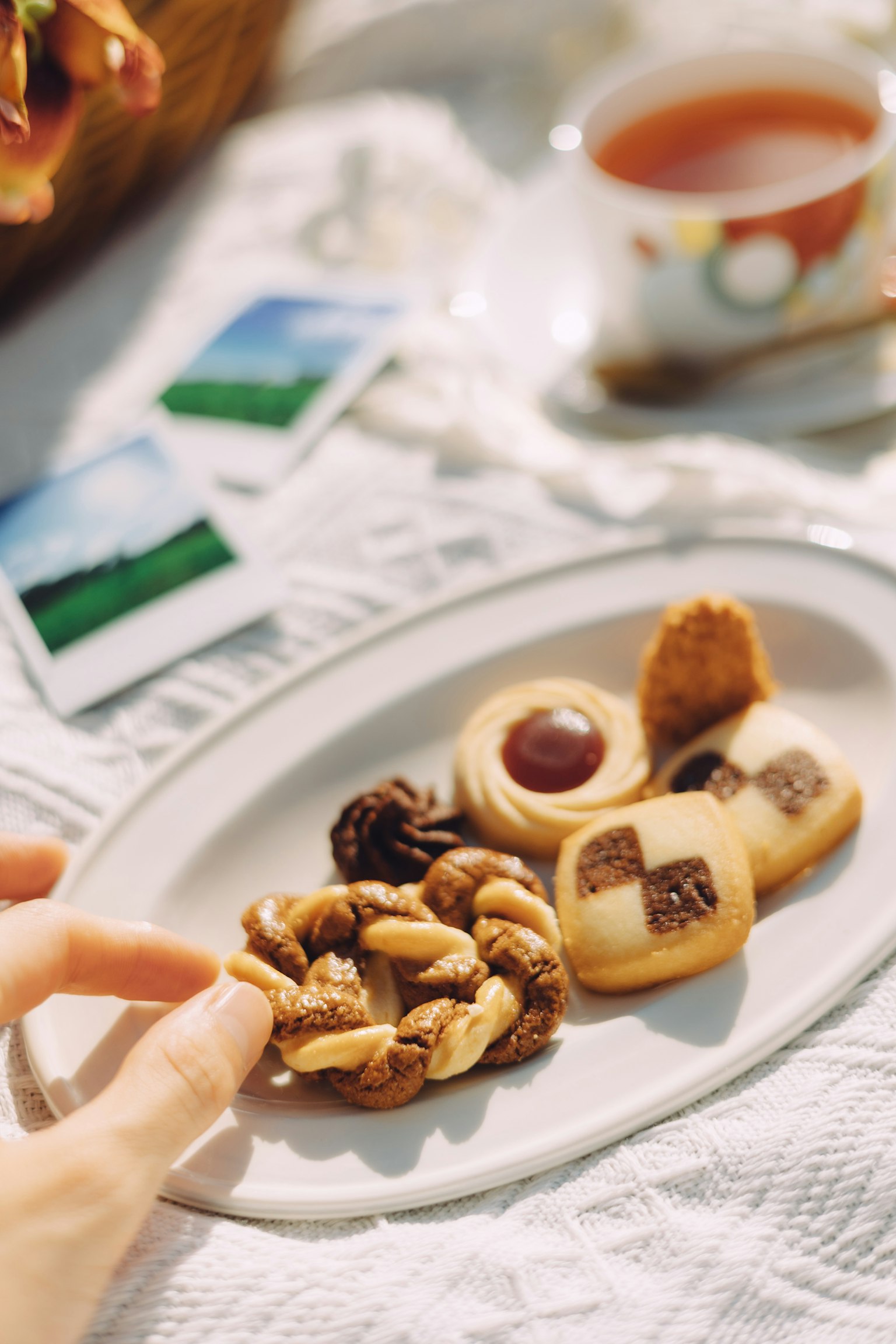 Một đĩa bánh quy và hạt với một tách trà ở phía sau