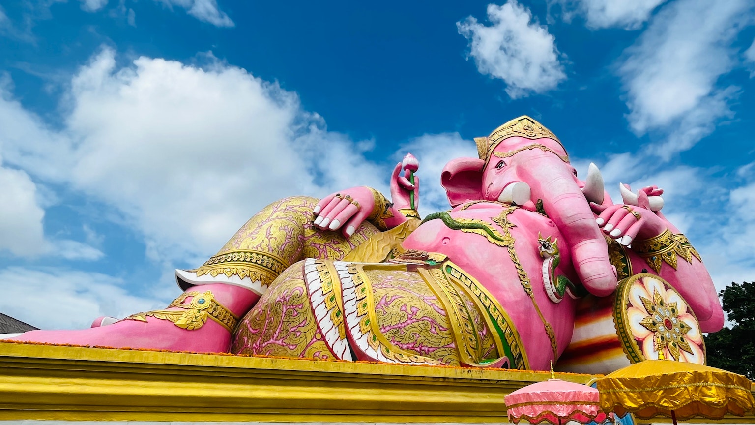 Eine große rosa Ganesha-Statue, die unter einem blauen Himmel liegt