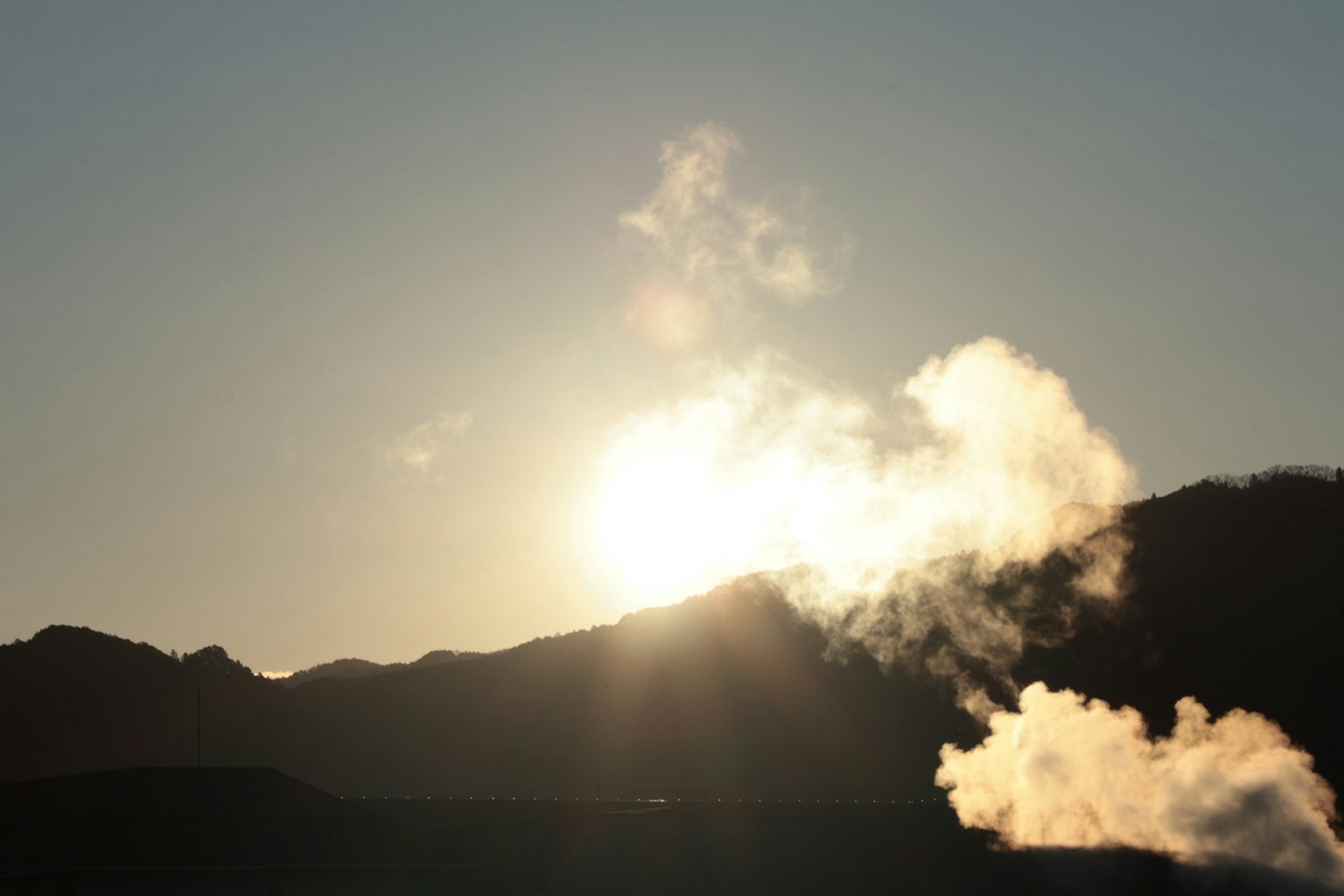 Alba sulle montagne con vapore che sale in primo piano
