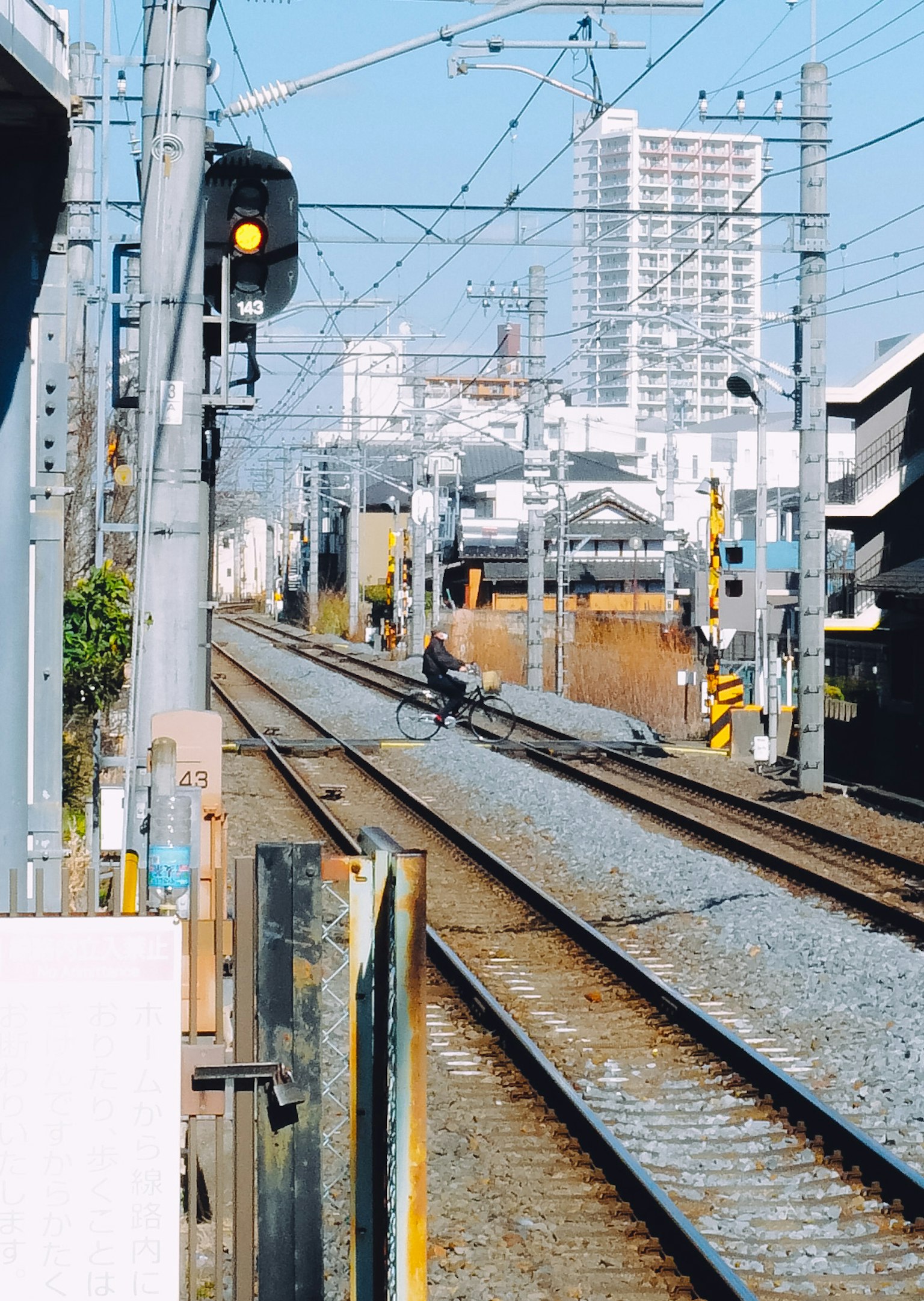 ภาพมุมมองของรางรถไฟพร้อมสัญญาณและอาคารในพื้นหลัง