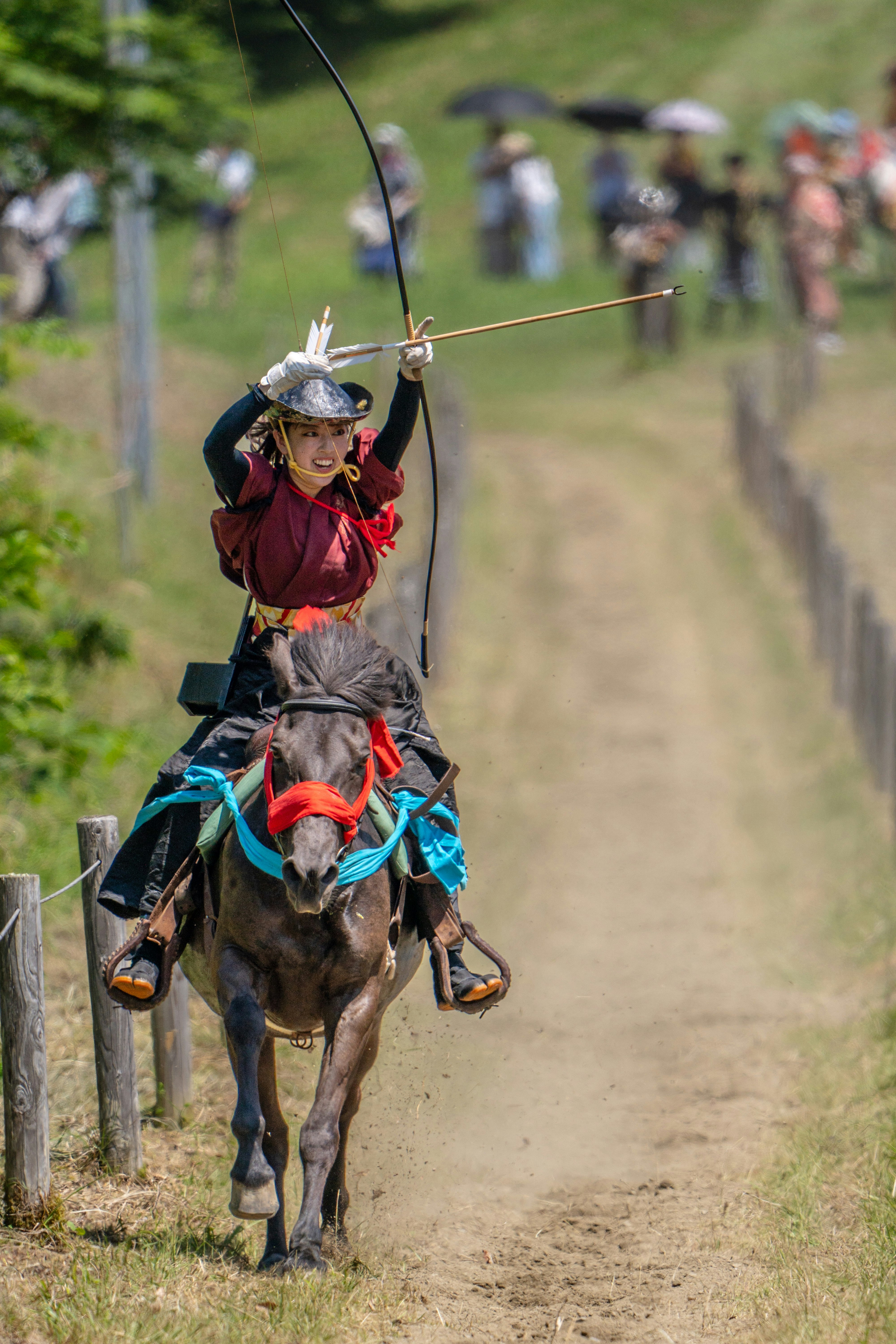 馬に乗った流鏑馬の射手が並走する観客の前を進む競技風景