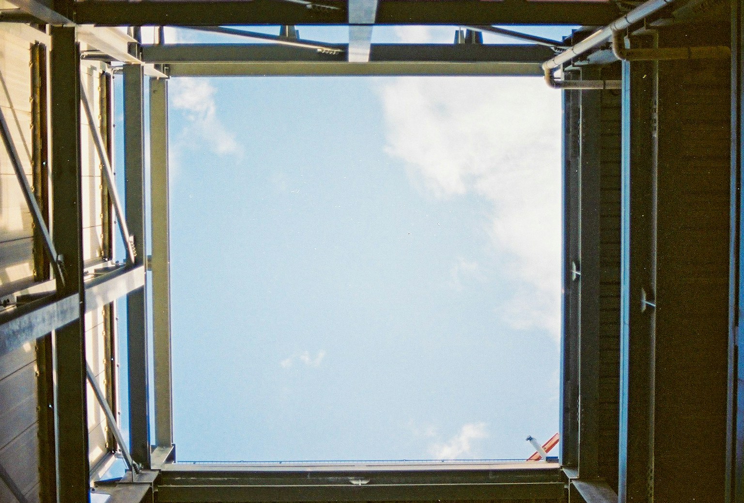 Blick auf den blauen Himmel und die Wolken durch eine Metallstruktur