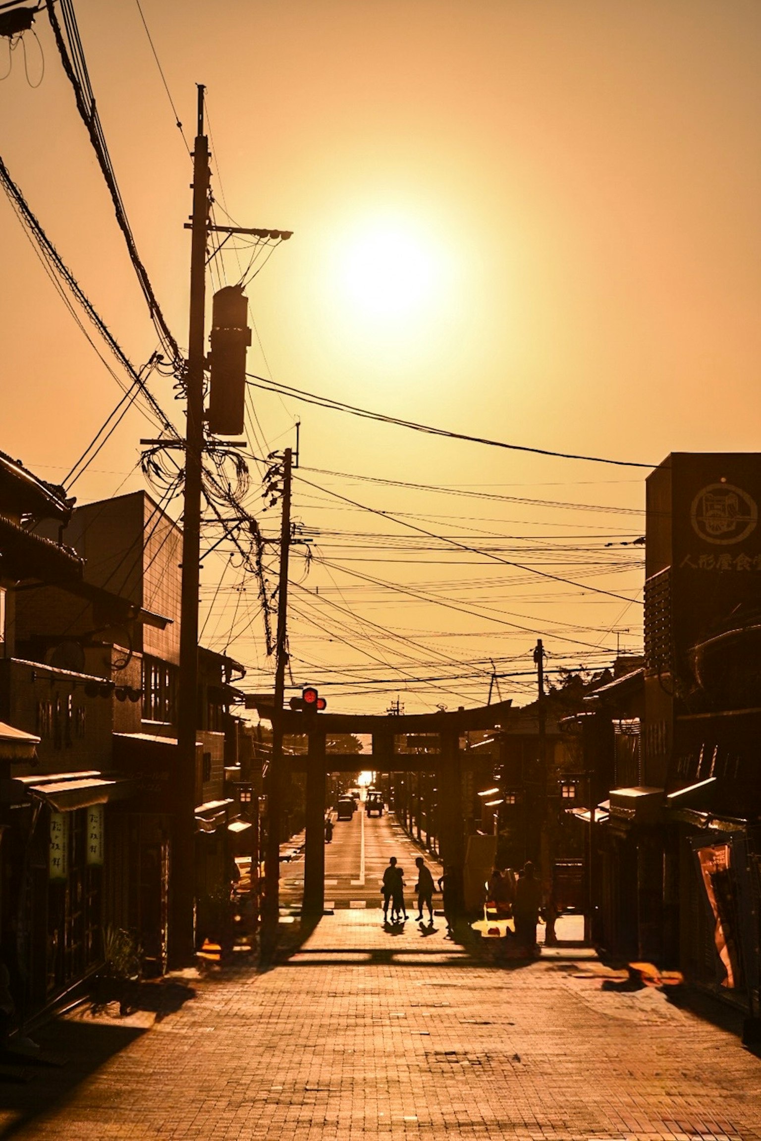 夕日が照らす街並みと電線が交差する風景