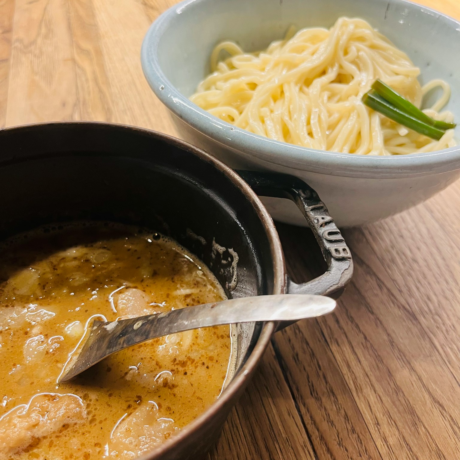 一张汤和面条的照片 棕色汤 白色面条 在木桌上