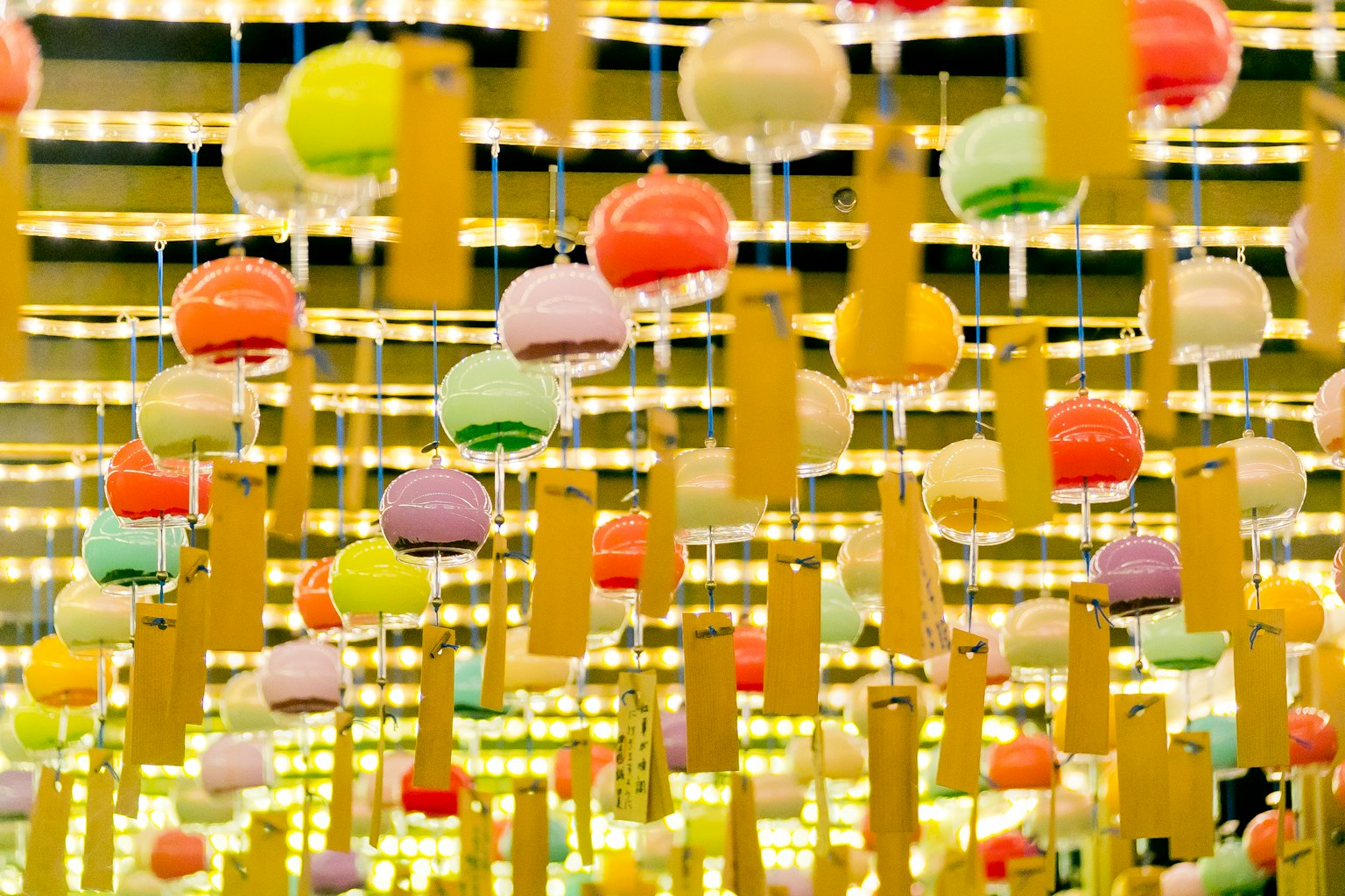 Campanas de viento coloridas y tiras amarillas colgantes en una exhibición vibrante