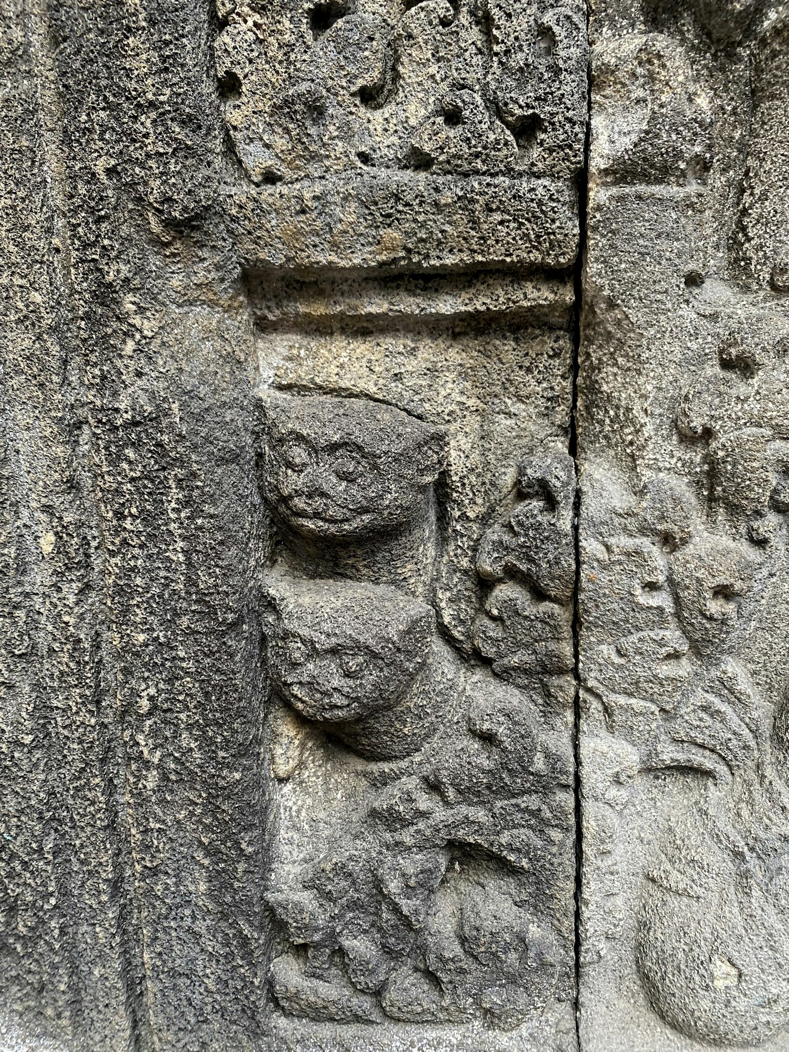 Detail einer alten Steinmauer mit katzenartigen Skulpturen und komplizierten Schnitzereien