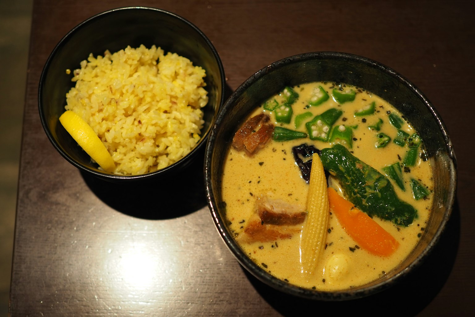 Creamy soup with colorful vegetables served with yellow rice and a slice of lemon