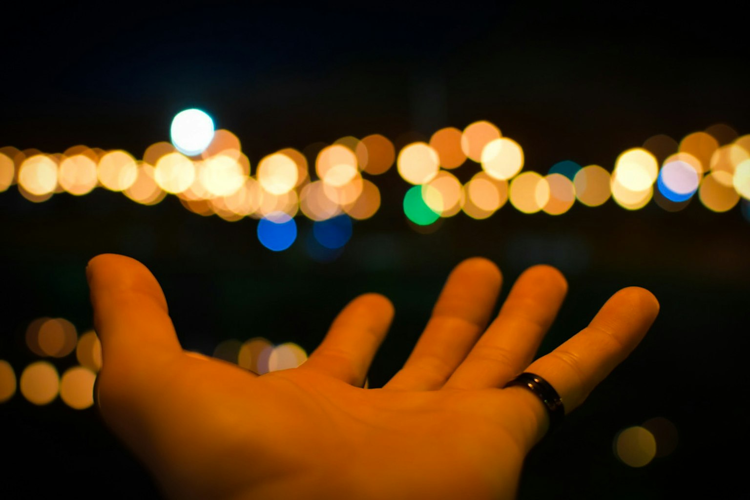 Mano tesa con luci colorate sfocate sullo sfondo